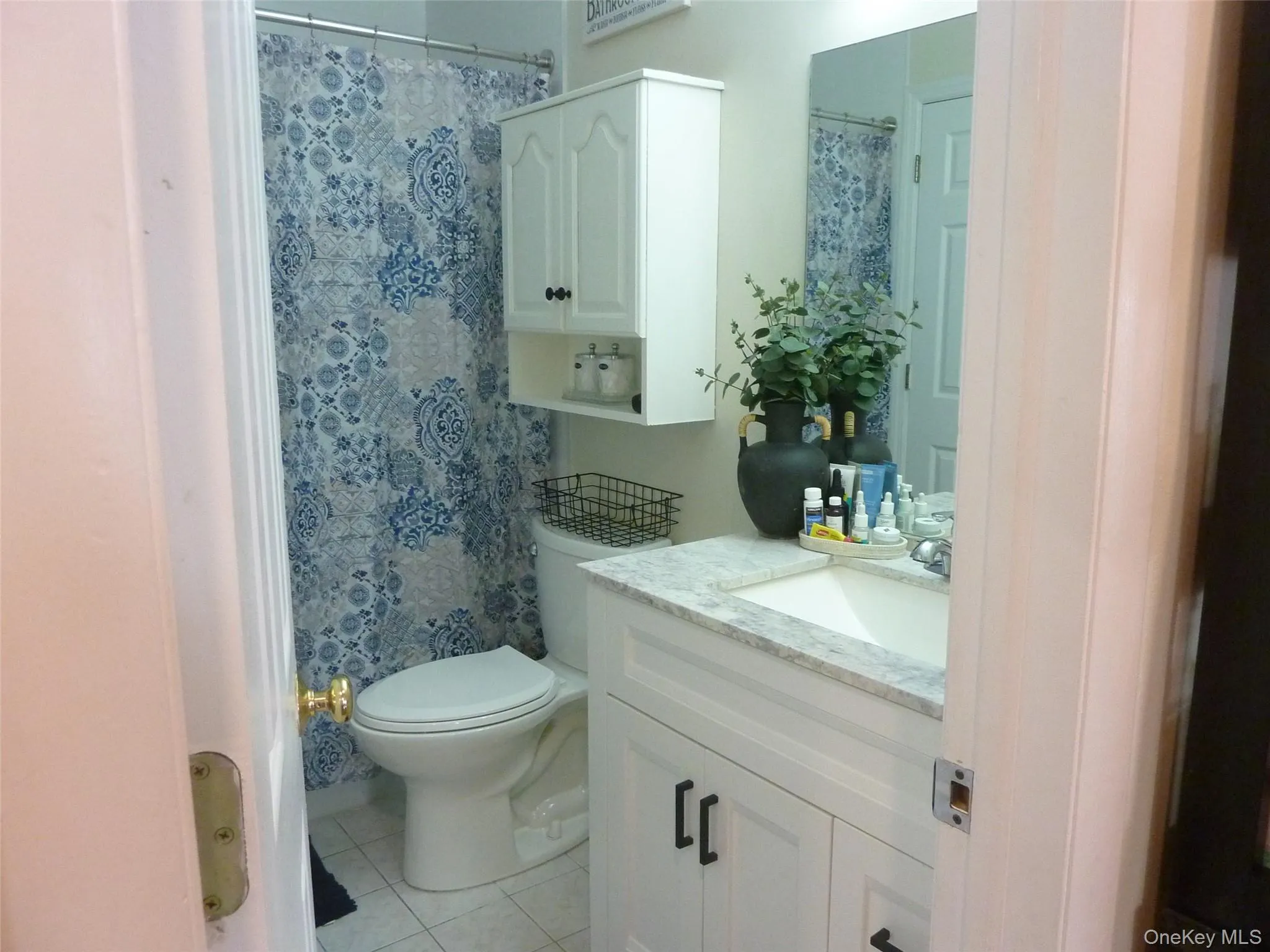 Bathroom featuring vanity, curtained shower, and light tile patterned floors Bathroom featuring vanity, curtained shower, and light tile patterned floors