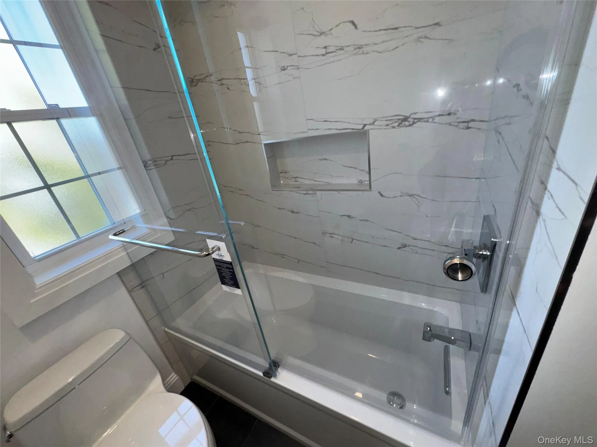 Bathroom featuring shower / bath combination with glass door and tile patterned floors Bathroom featuring shower / bath combination with glass door and tile patterned floors