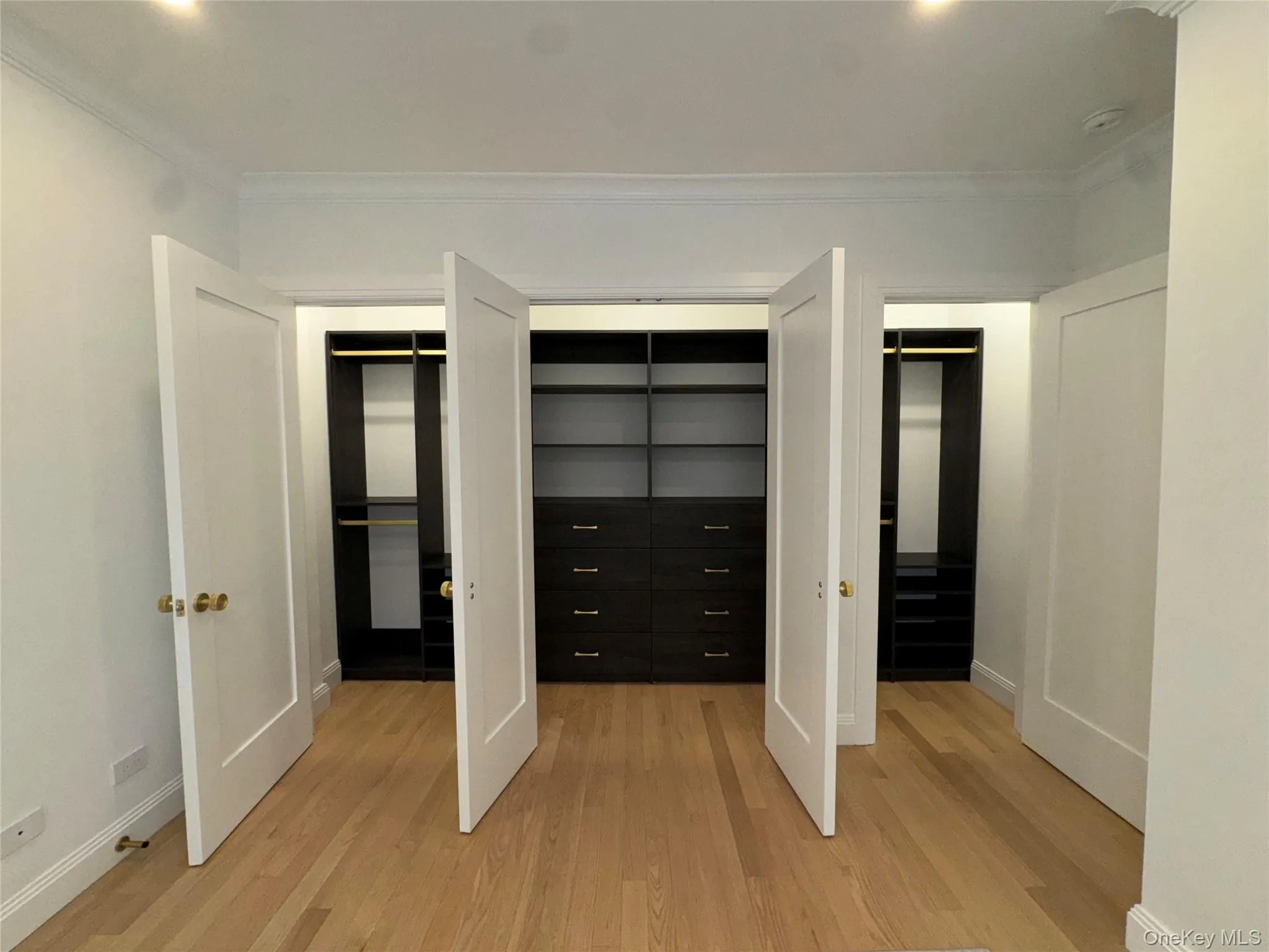 Unfurnished bedroom with two closets, crown molding, light wood-style flooring, and recessed lighting Unfurnished bedroom with two closets, crown molding, light wood-style flooring, and recessed lighting