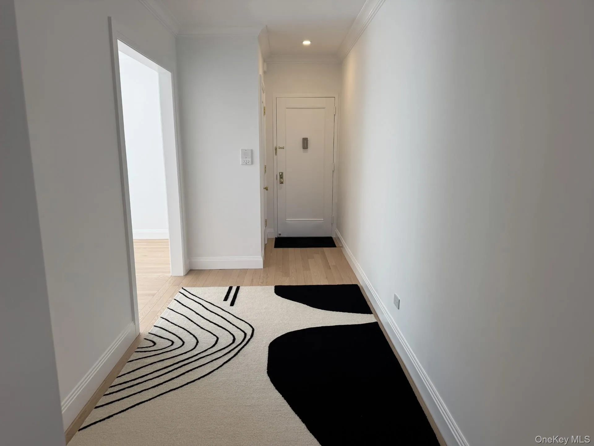 Hallway with ornamental molding, light wood finished floors, and recessed lighting Hallway with ornamental molding, light wood finished floors, and recessed lighting