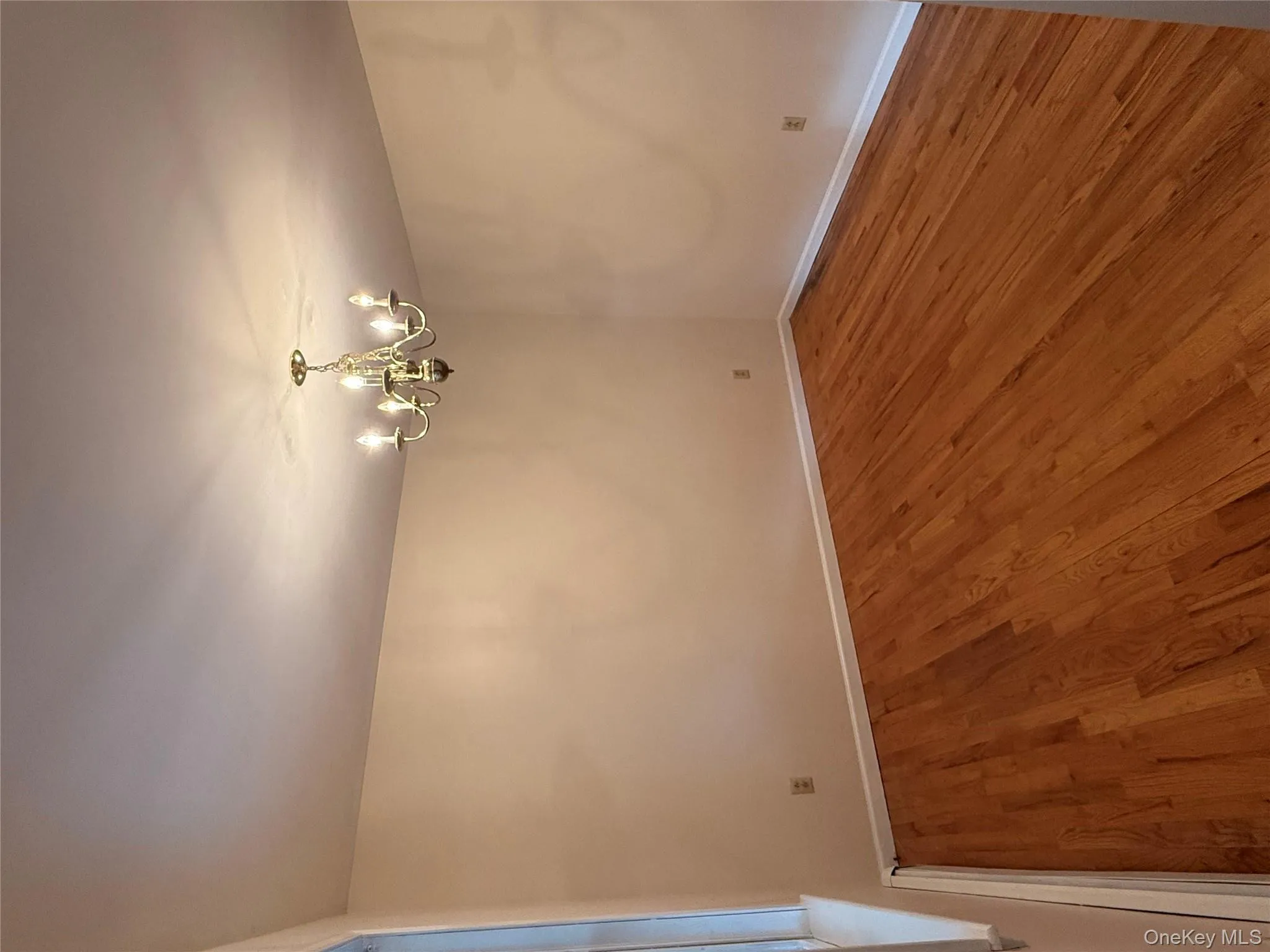 Unfurnished room featuring wood finished floors, a chandelier, and a baseboard radiator Unfurnished room featuring wood finished floors, a chandelier, and a baseboard radiator