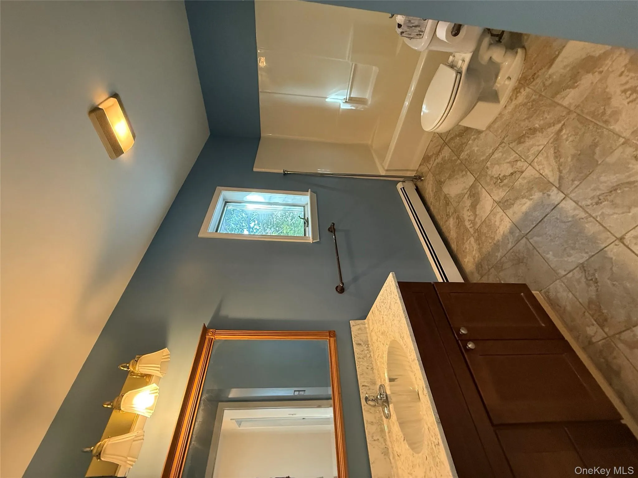 Full bath with a baseboard heating unit, vanity, and shower / bath combination Full bath with a baseboard heating unit, vanity, and shower / bath combination