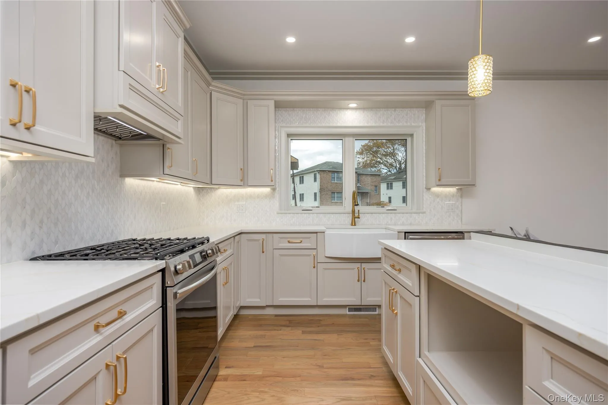 Kitchen with stainless steel gas range oven, light wood finished floors, backsplash, decorative light fixtures, and recessed lighting Kitchen with stainless steel gas range oven, light wood finished floors, backsplash, decorative light fixtures, and recessed lighting