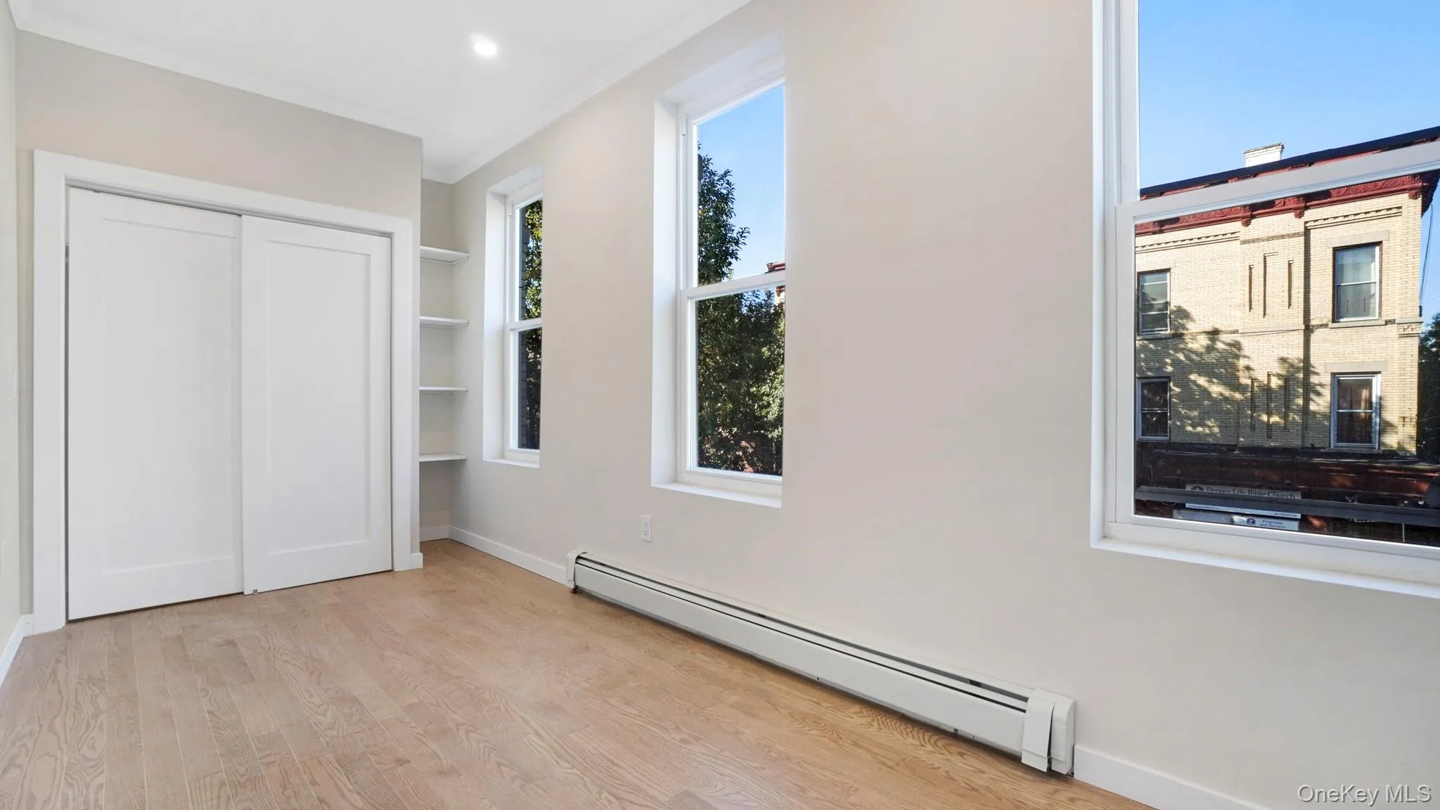 Unfurnished bedroom featuring a baseboard heating unit, light wood finished floors, a closet, ornamental molding, and recessed lighting Unfurnished bedroom featuring a baseboard heating unit, light wood finished floors, a closet, ornamental molding, and recessed lighting