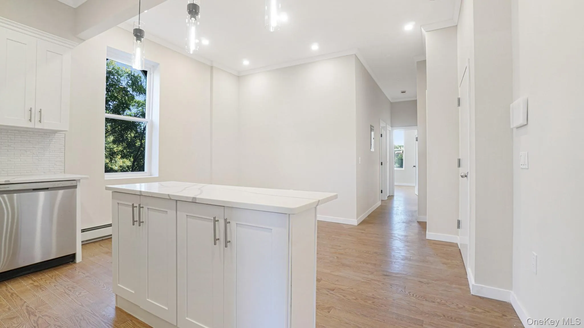 Kitchen featuring white cabinets, stainless steel dishwasher, pendant lighting, backsplash, and light wood-type flooring Kitchen featuring white cabinets, stainless steel dishwasher, pendant lighting, backsplash, and light wood-type flooring