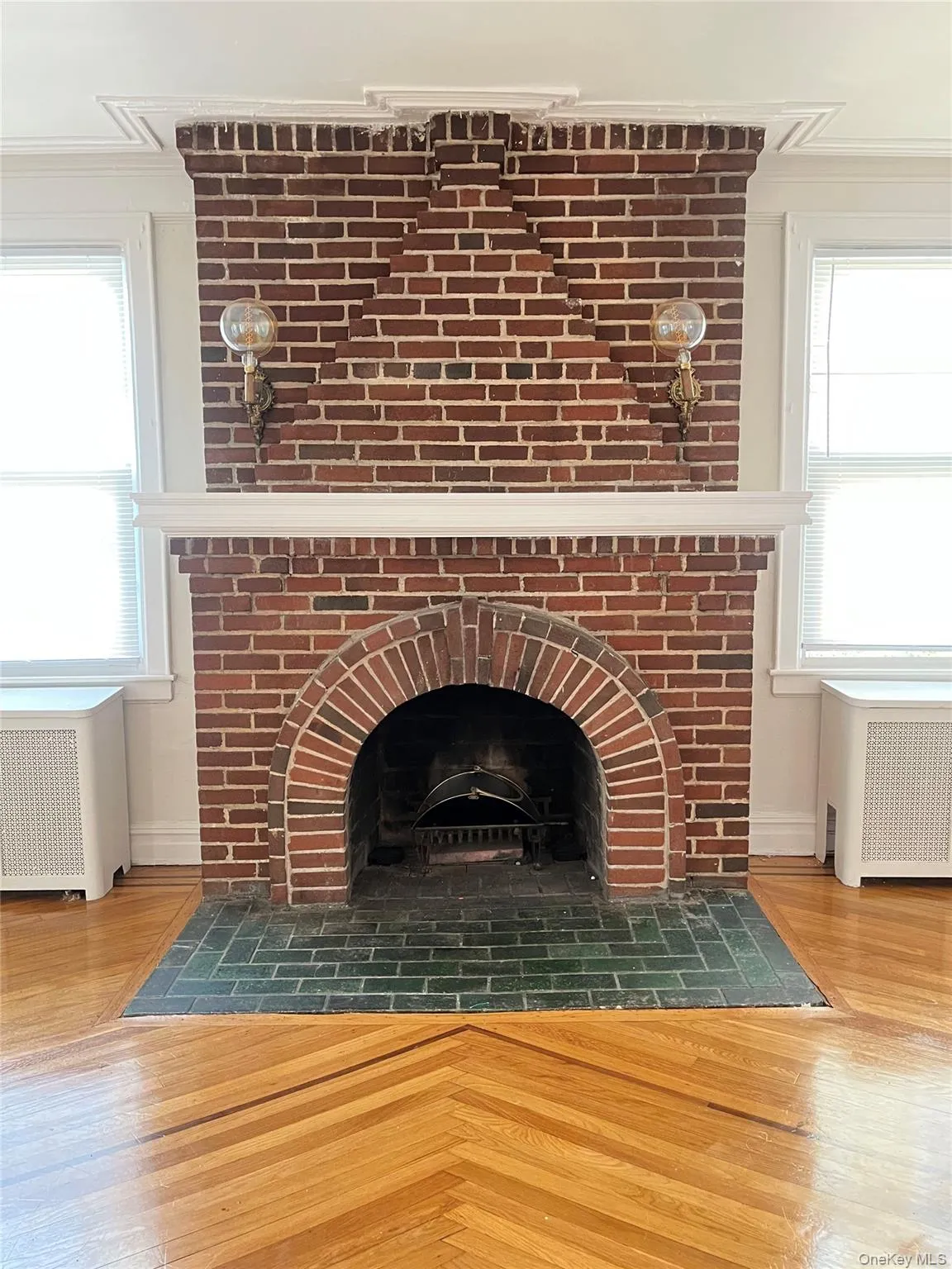 Detailed view of wood finished floors, radiator, a fireplace, and crown molding Detailed view of wood finished floors, radiator, a fireplace, and crown molding