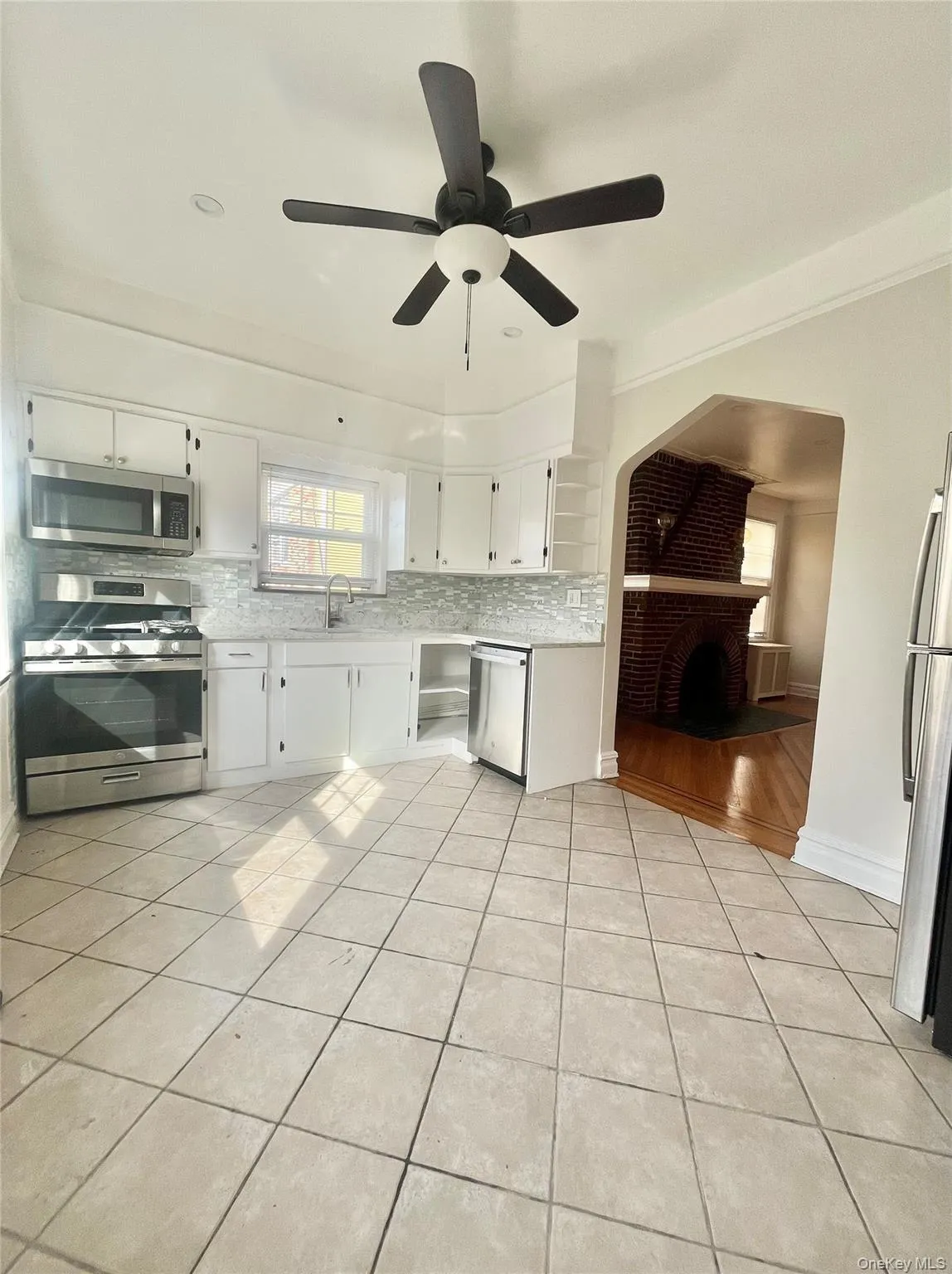 Kitchen with appliances with stainless steel finishes, white cabinetry, backsplash, and light tile patterned floors Kitchen with appliances with stainless steel finishes, white cabinetry, backsplash, and light tile patterned floors