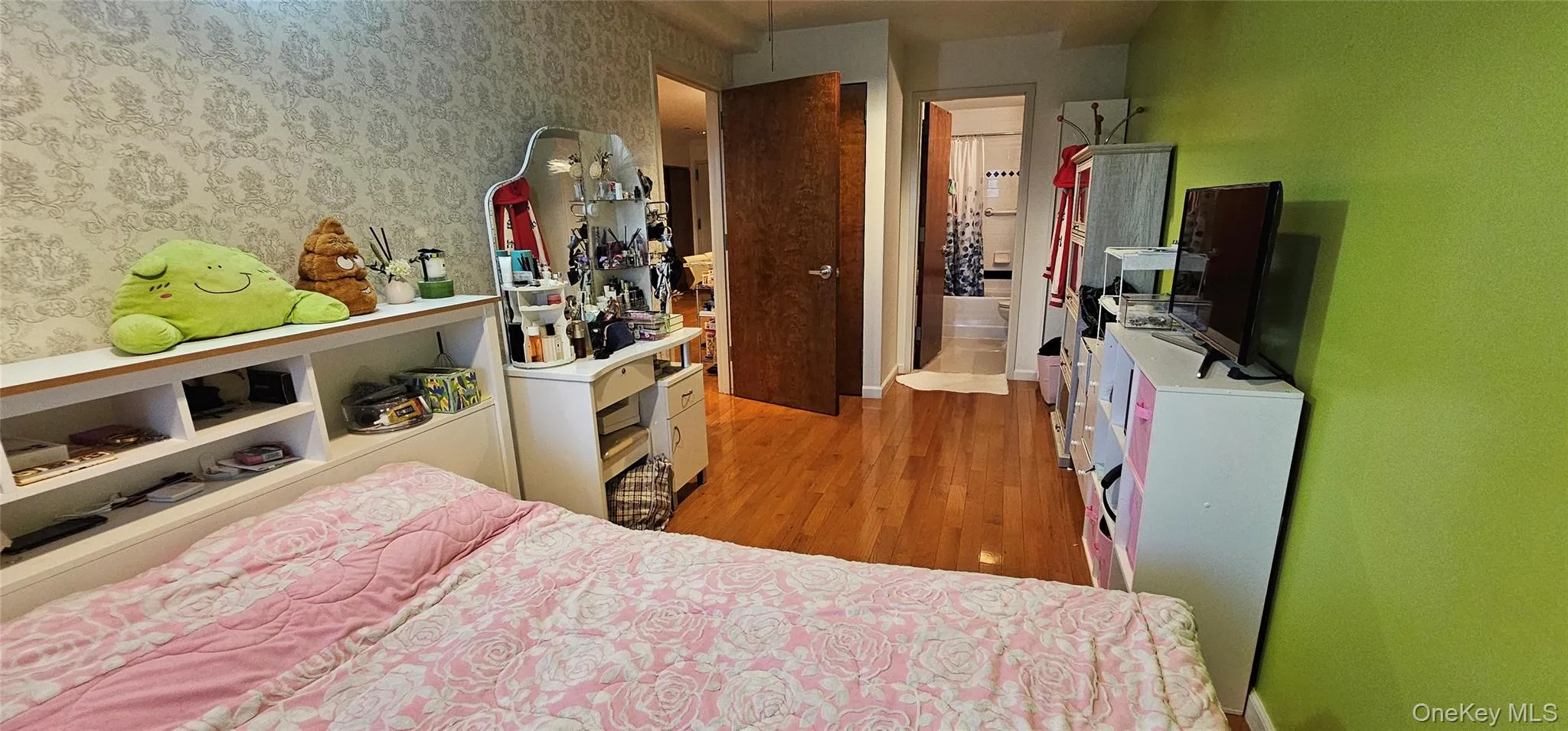 Bedroom with light wood-type flooring and wallpapered walls Bedroom with light wood-type flooring and wallpapered walls