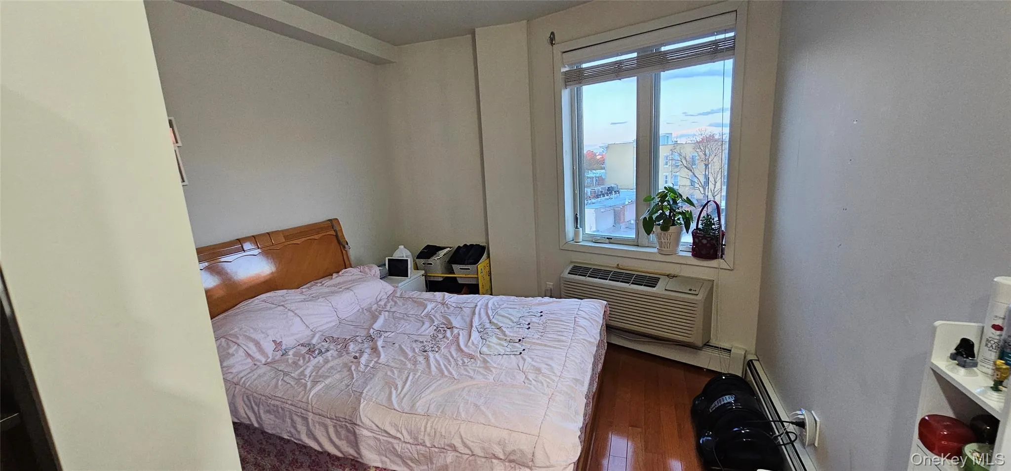 Bedroom featuring dark wood-style flooring, an AC wall unit, and a baseboard radiator Bedroom featuring dark wood-style flooring, an AC wall unit, and a baseboard radiator