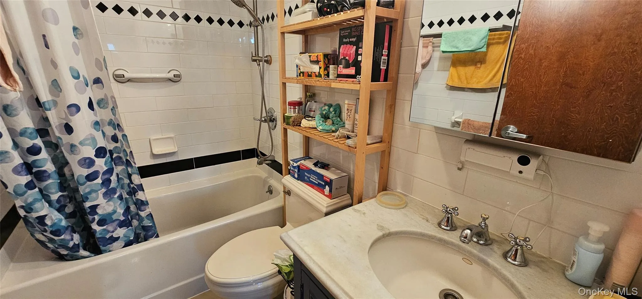 Full bathroom featuring shower / tub combo with curtain, vanity, and tasteful backsplash Full bathroom featuring shower / tub combo with curtain, vanity, and tasteful backsplash