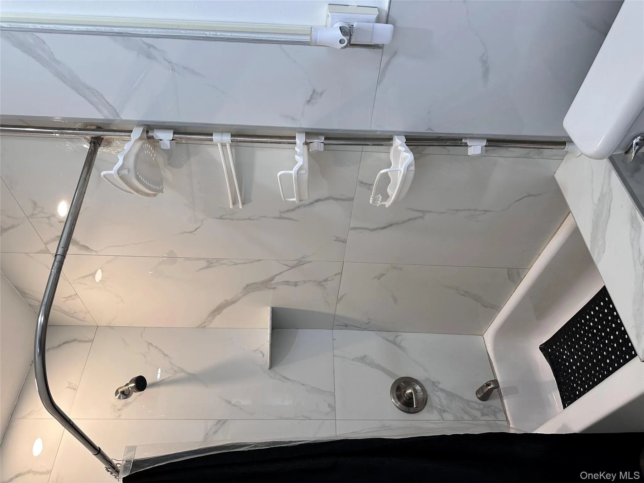 Full bath featuring a combined bath / shower with marble appearance and toilet Full bath featuring a combined bath / shower with marble appearance and toilet