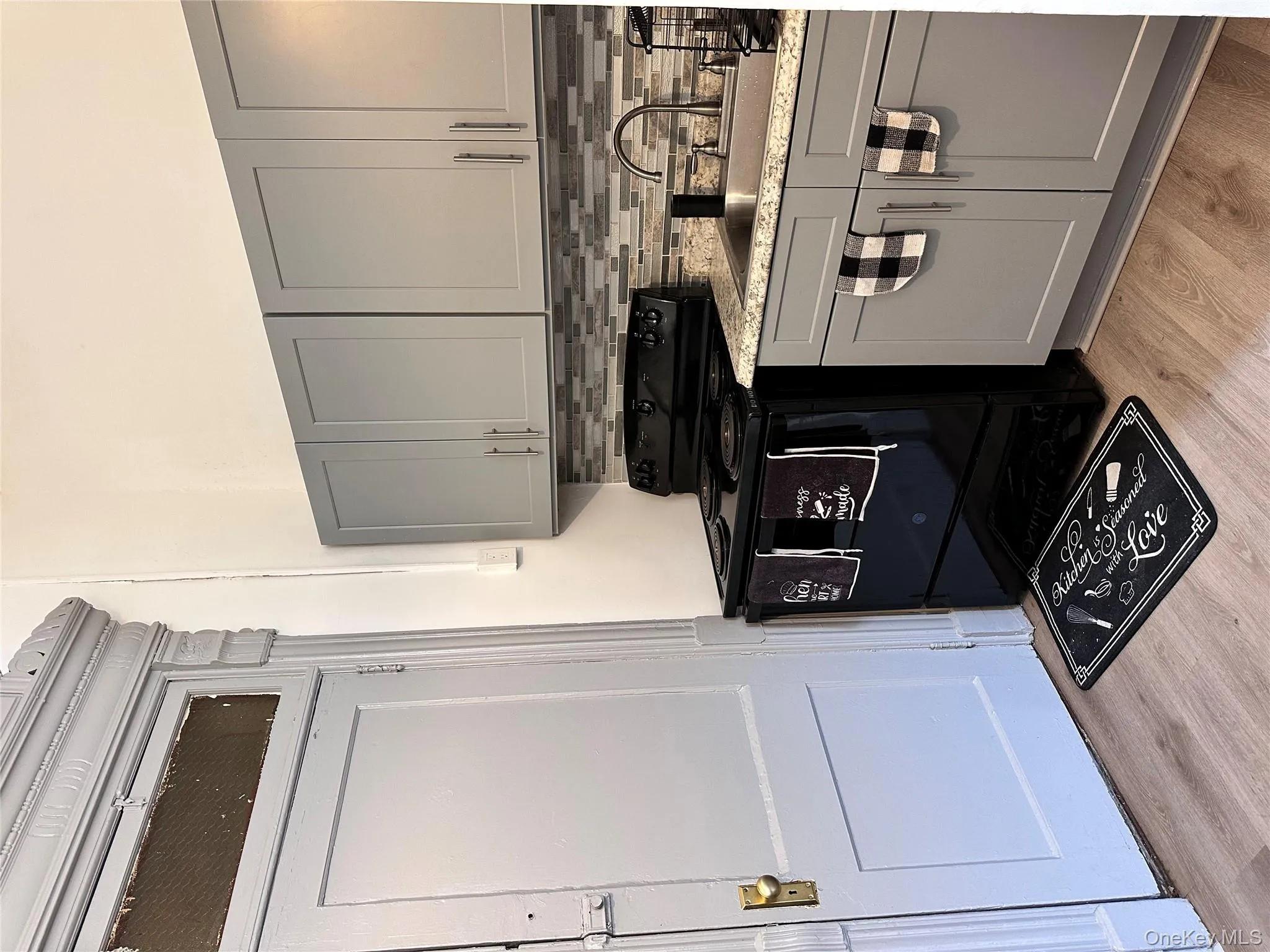 Kitchen with gray cabinets, white stove, light wood finished floors, tasteful backsplash, and light stone counters Kitchen with gray cabinets, white stove, light wood finished floors, tasteful backsplash, and light stone counters