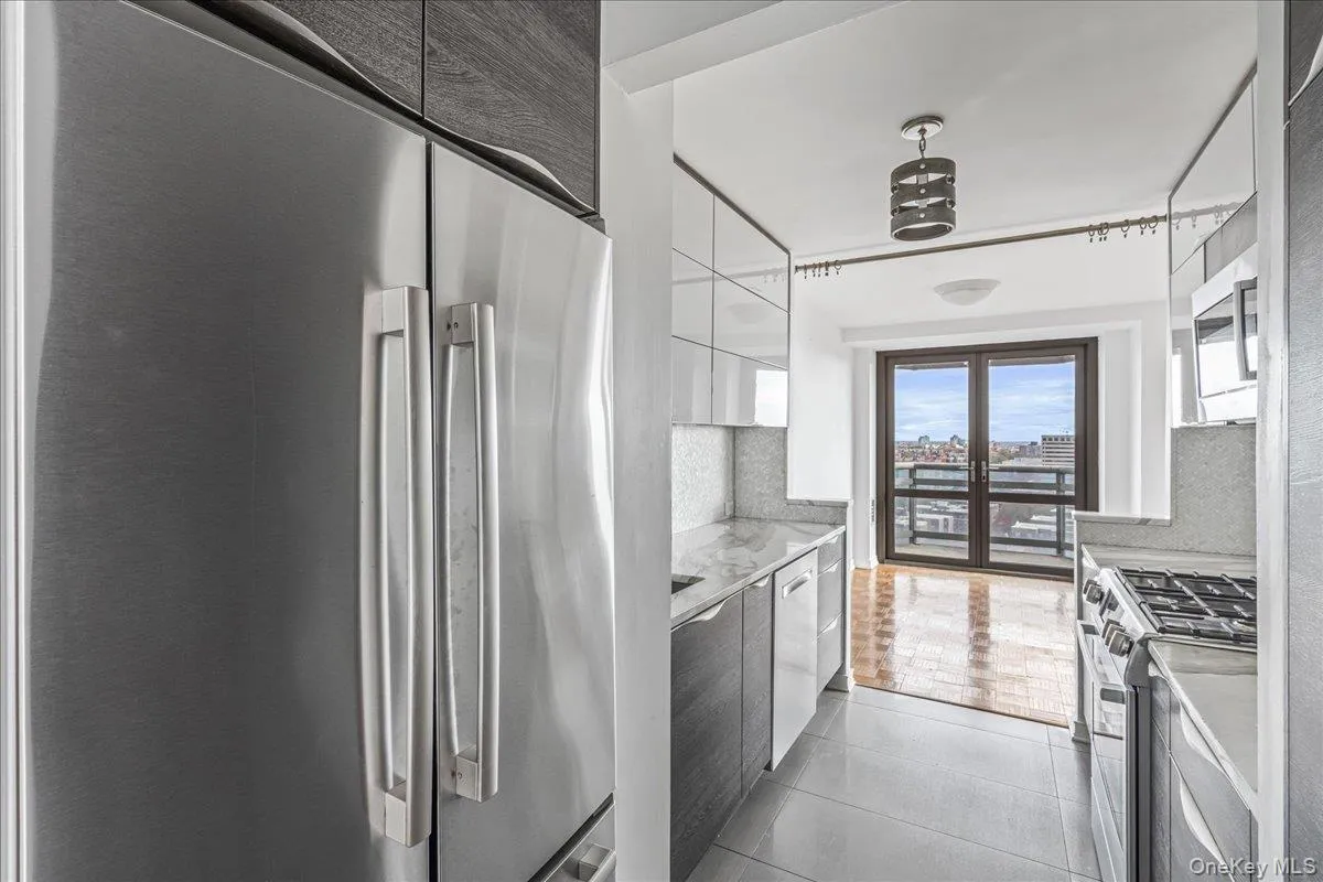 Kitchen with stainless steel appliances, white cabinetry, modern cabinets, light tile patterned floors, and light stone countertops Kitchen with stainless steel appliances, white cabinetry, modern cabinets, light tile patterned floors, and light stone countertops