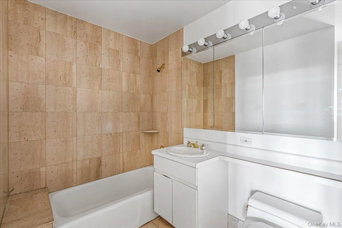 Bathroom with vanity, shower / bath combination, and tile walls Bathroom with vanity, shower / bath combination, and tile walls