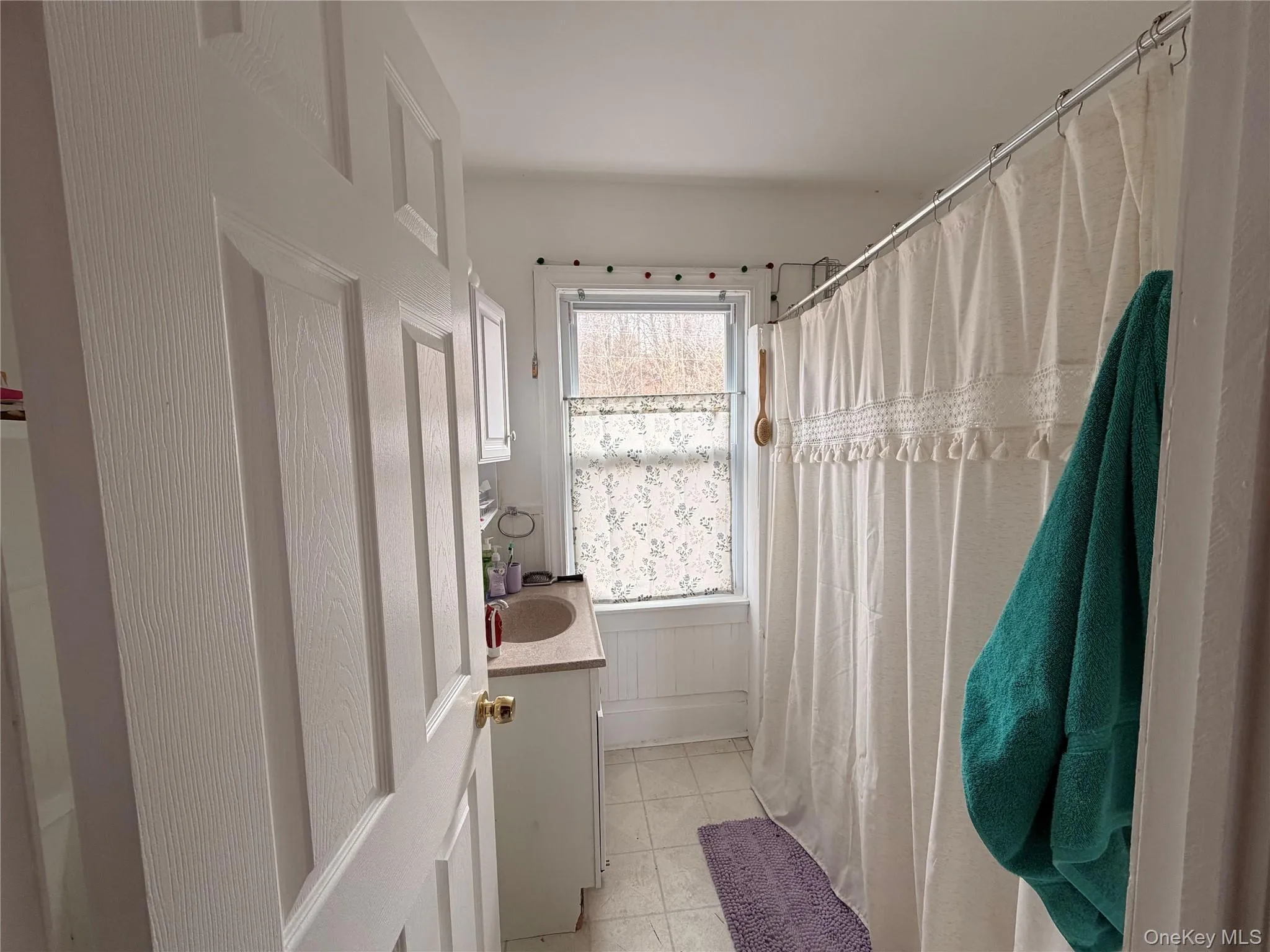 Bathroom with vanity, curtained shower, and light tile patterned flooring Bathroom with vanity, curtained shower, and light tile patterned flooring