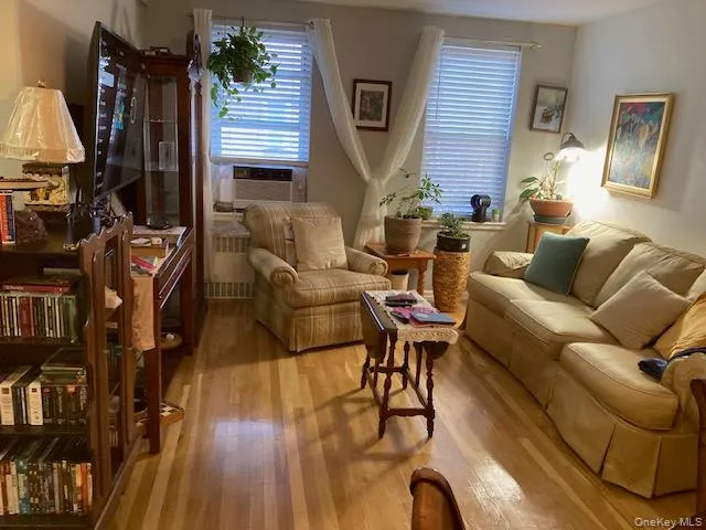 Living area featuring wood finished floors, radiator heating unit, and cooling unit Living area featuring wood finished floors, radiator heating unit, and cooling unit