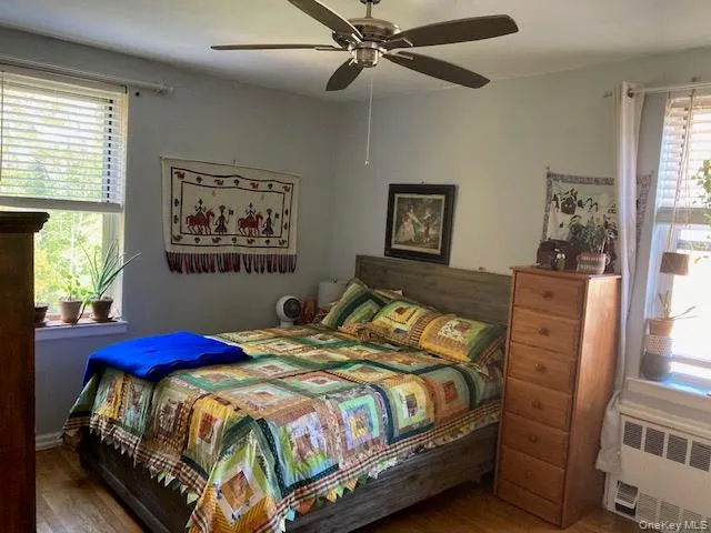 Bedroom with radiator, wood finished floors, and a ceiling fan Bedroom with radiator, wood finished floors, and a ceiling fan
