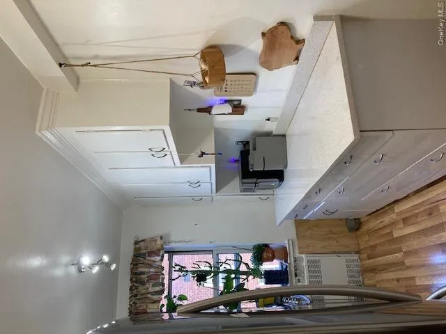 Kitchen with light wood finished floors, white cabinetry, fridge, light stone counters, and radiator heating unit Kitchen with light wood finished floors, white cabinetry, fridge, light stone counters, and radiator heating unit