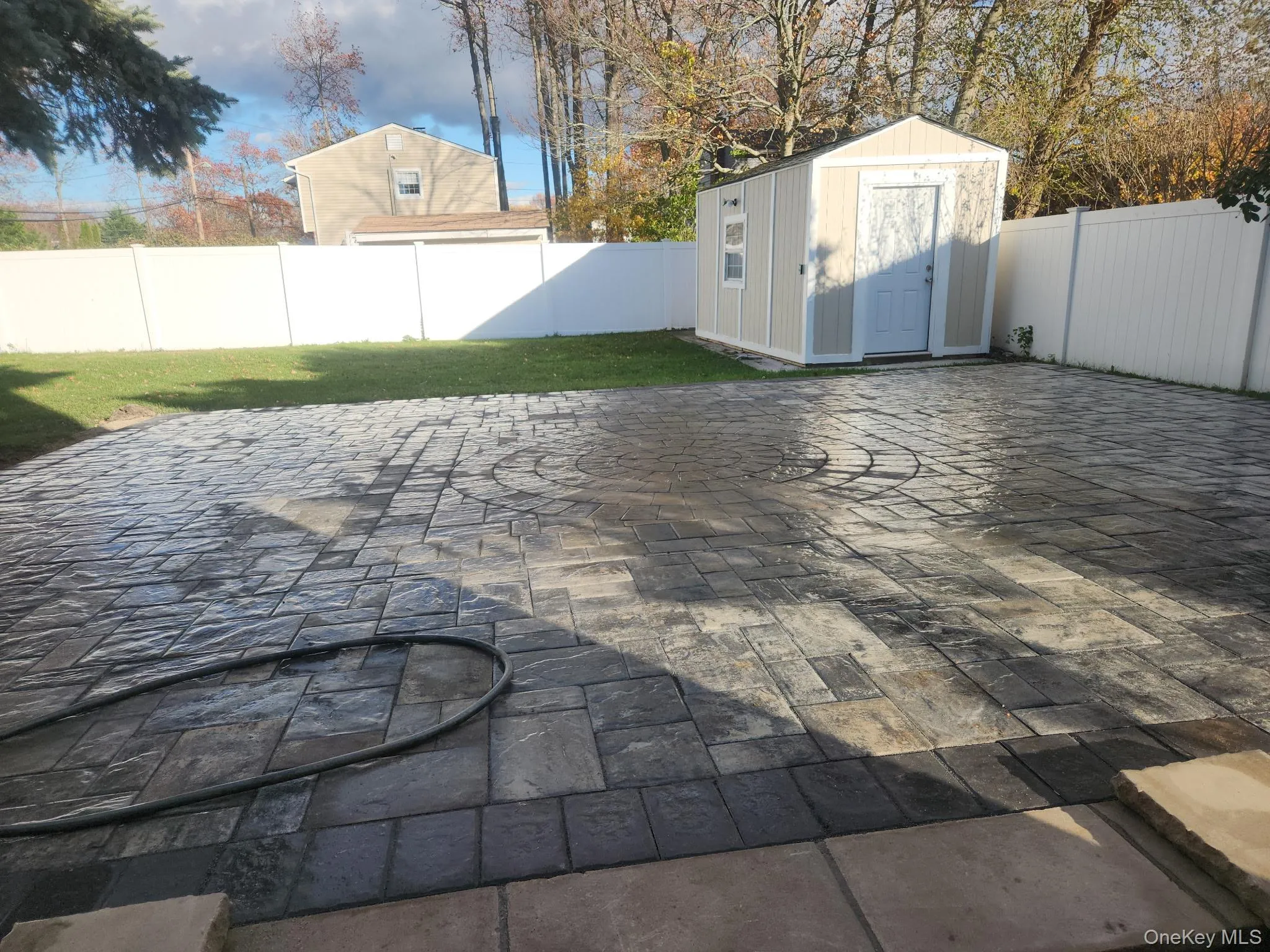 Fenced backyard with a storage unit and a patio Fenced backyard with a storage unit and a patio