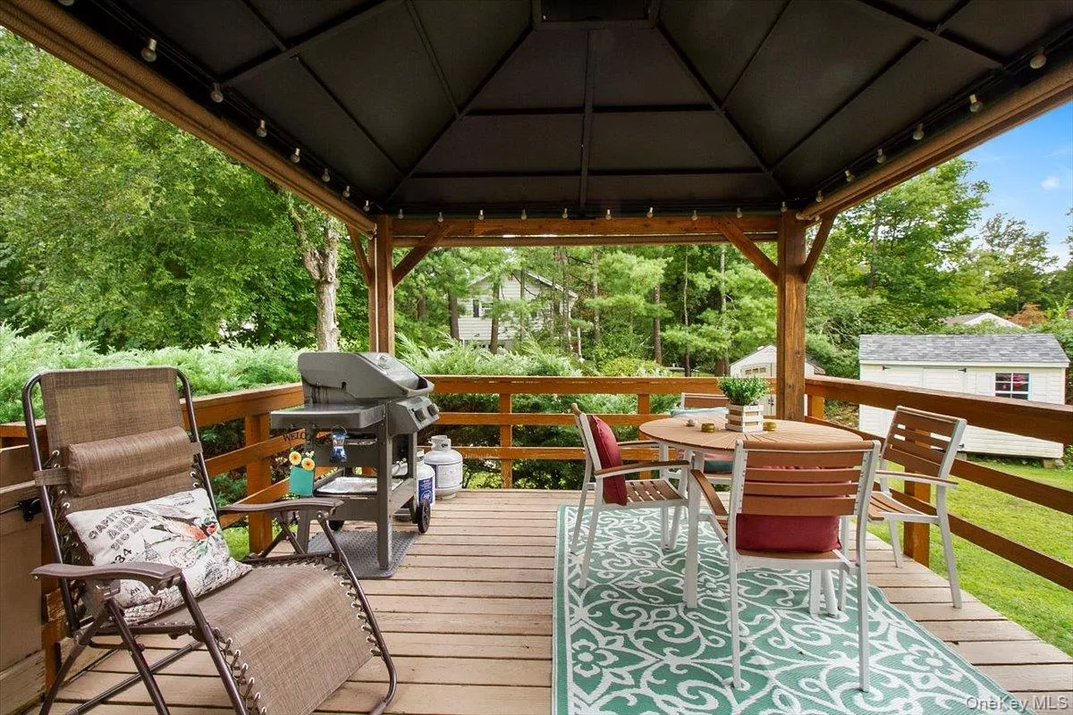 Wooden terrace with a grill, a gazebo, and outdoor dining space Wooden terrace with a grill, a gazebo, and outdoor dining space