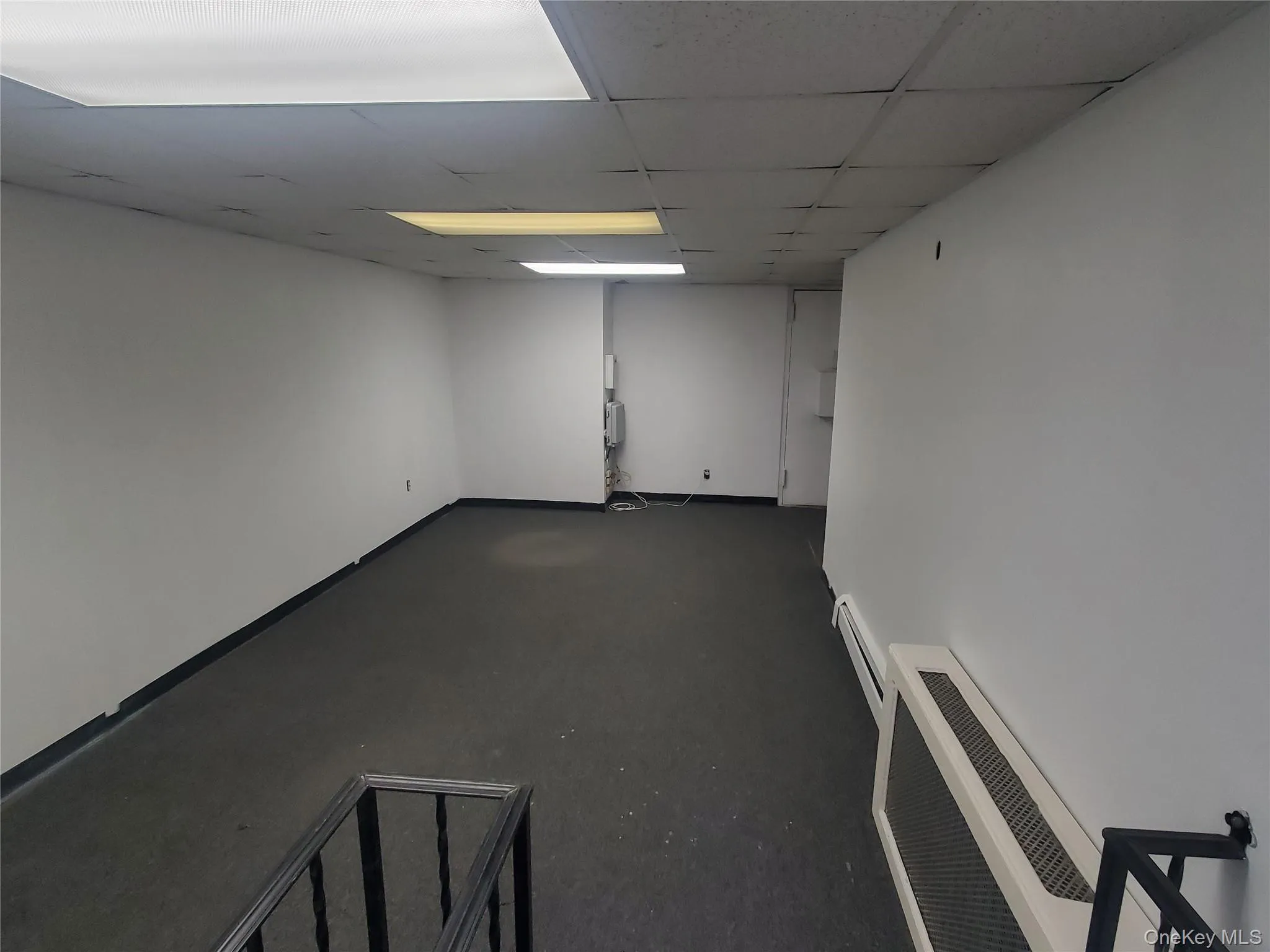 Main office area featuring a paneled ceiling and a baseboard heating unit Main office area featuring a paneled ceiling and a baseboard heating unit