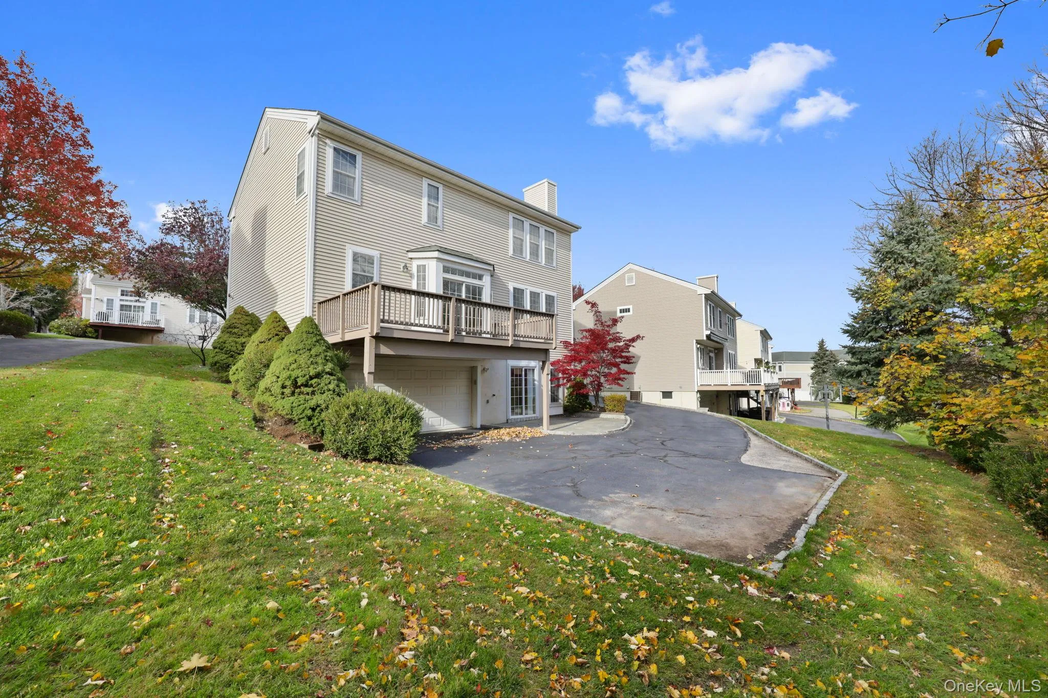 Rear view of house featuring a yard, a chimney, asphalt driveway, a patio, and a wooden deck Rear view of house featuring a yard, a chimney, asphalt driveway, a patio, and a wooden deck