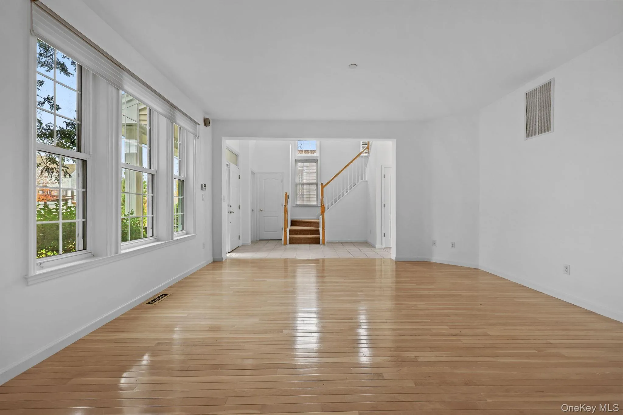 Unfurnished living room featuring hardwood / wood-style floors and stairway Unfurnished living room featuring hardwood / wood-style floors and stairway