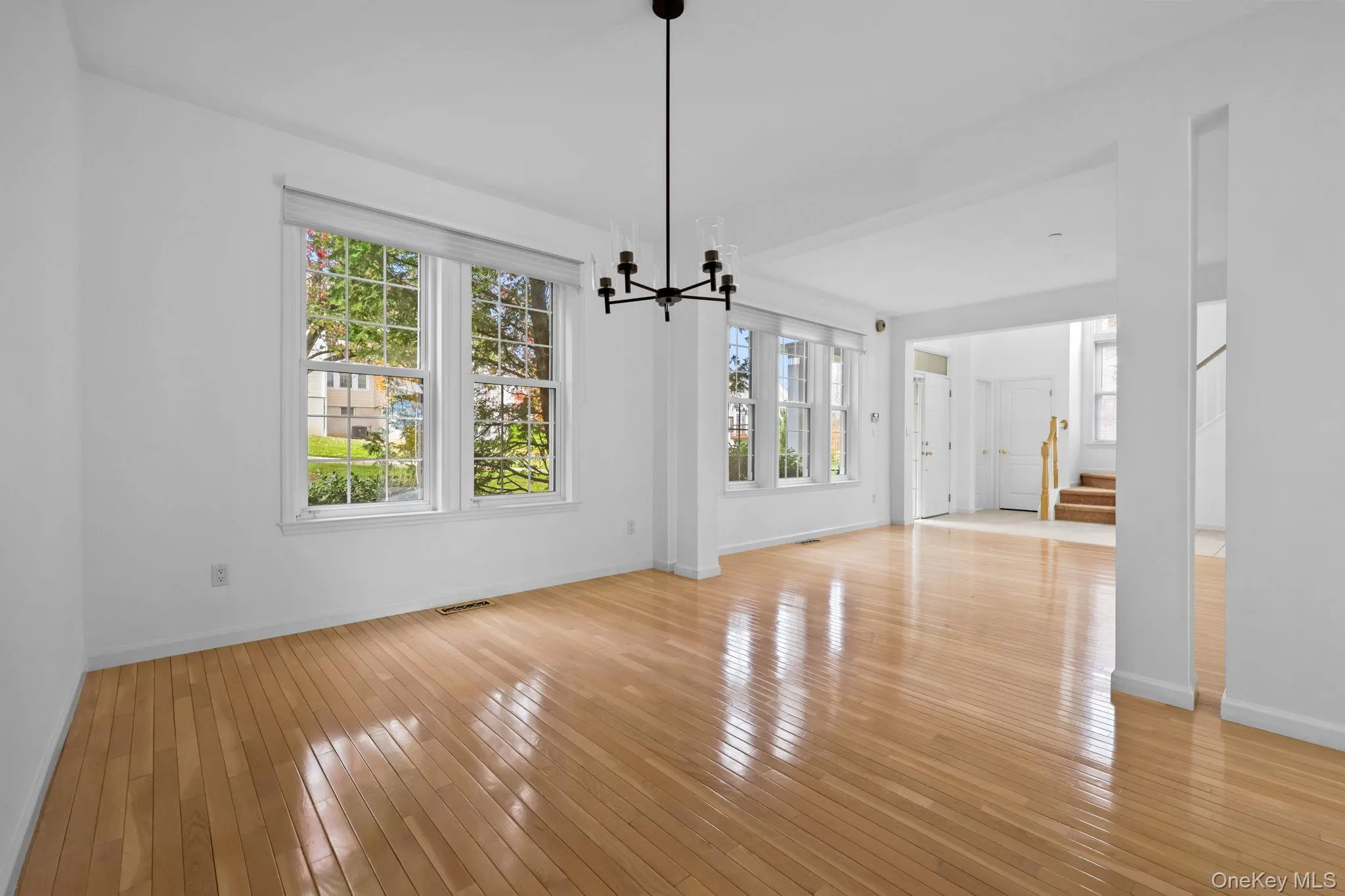 Unfurnished dining area with stairway, healthy amount of natural light, a chandelier, and light wood-style flooring Unfurnished dining area with stairway, healthy amount of natural light, a chandelier, and light wood-style flooring