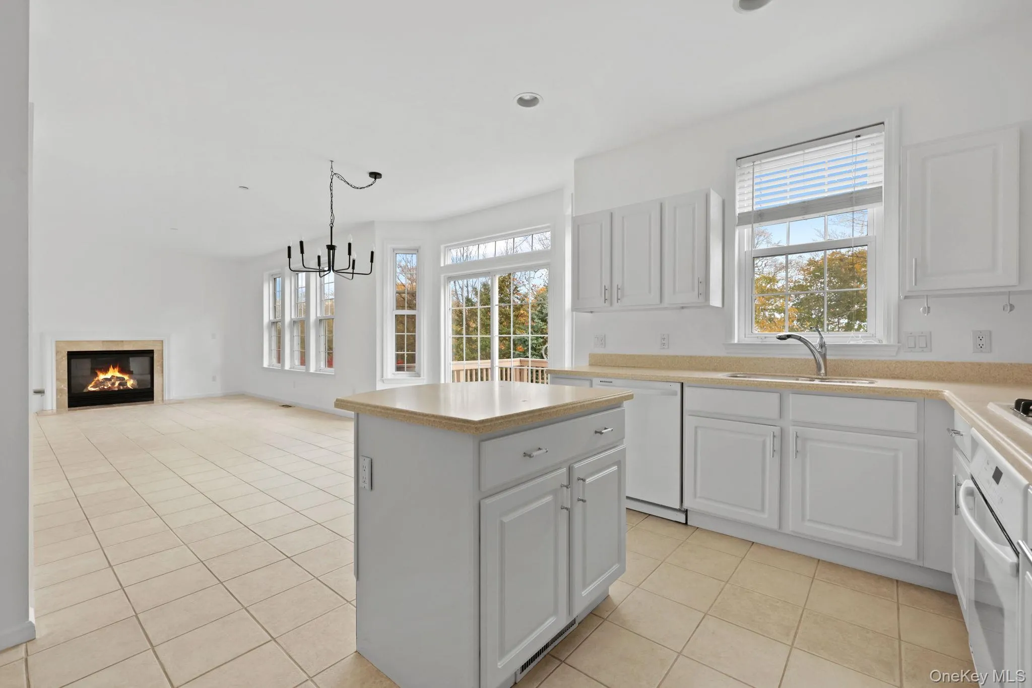 Kitchen with a glass covered fireplace, healthy amount of natural light, a kitchen island, light tile patterned floors, and recessed lighting Kitchen with a glass covered fireplace, healthy amount of natural light, a kitchen island, light tile patterned floors, and recessed lighting