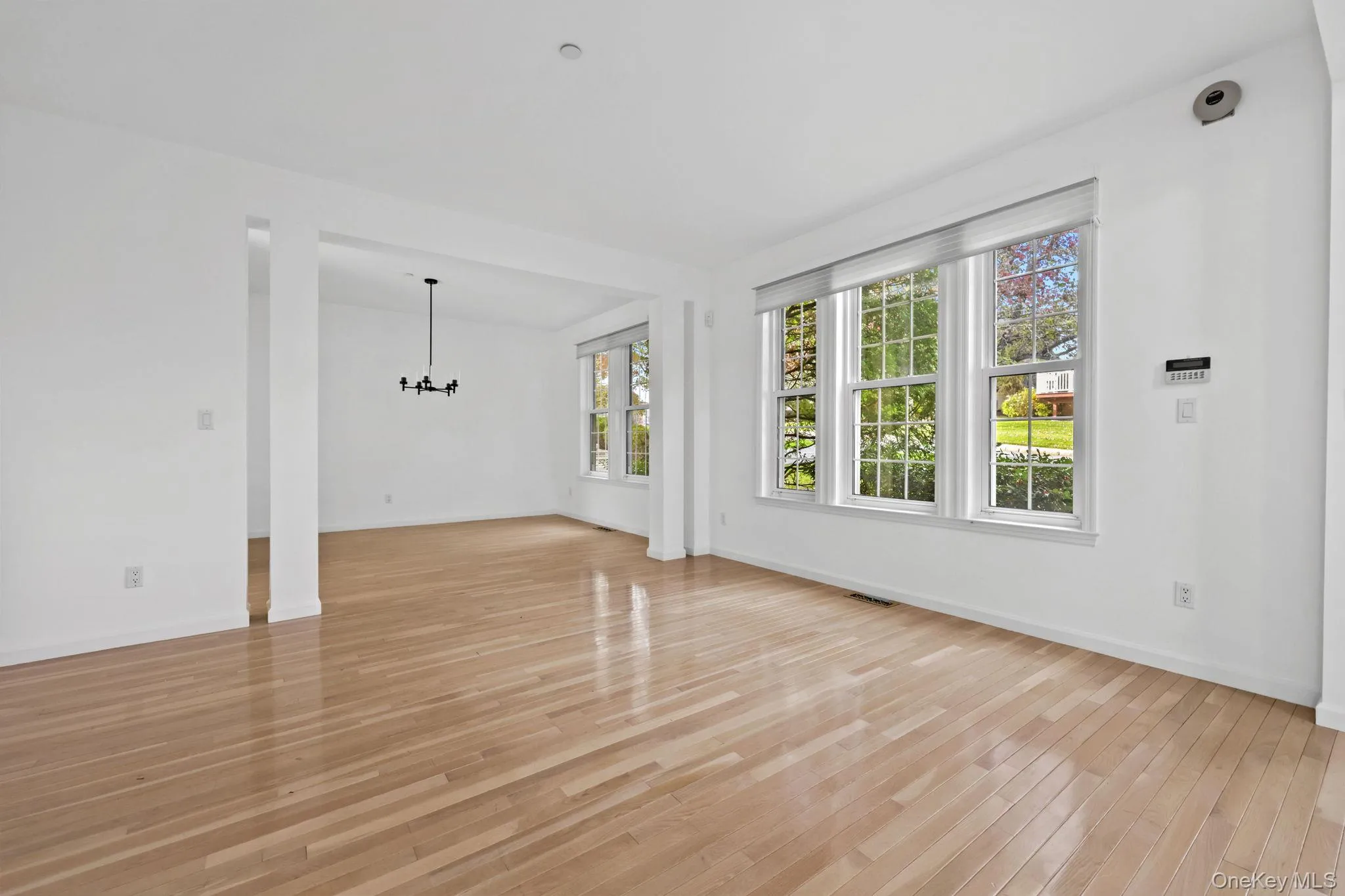 Unfurnished living room featuring a chandelier and light wood finished floors Unfurnished living room featuring a chandelier and light wood finished floors