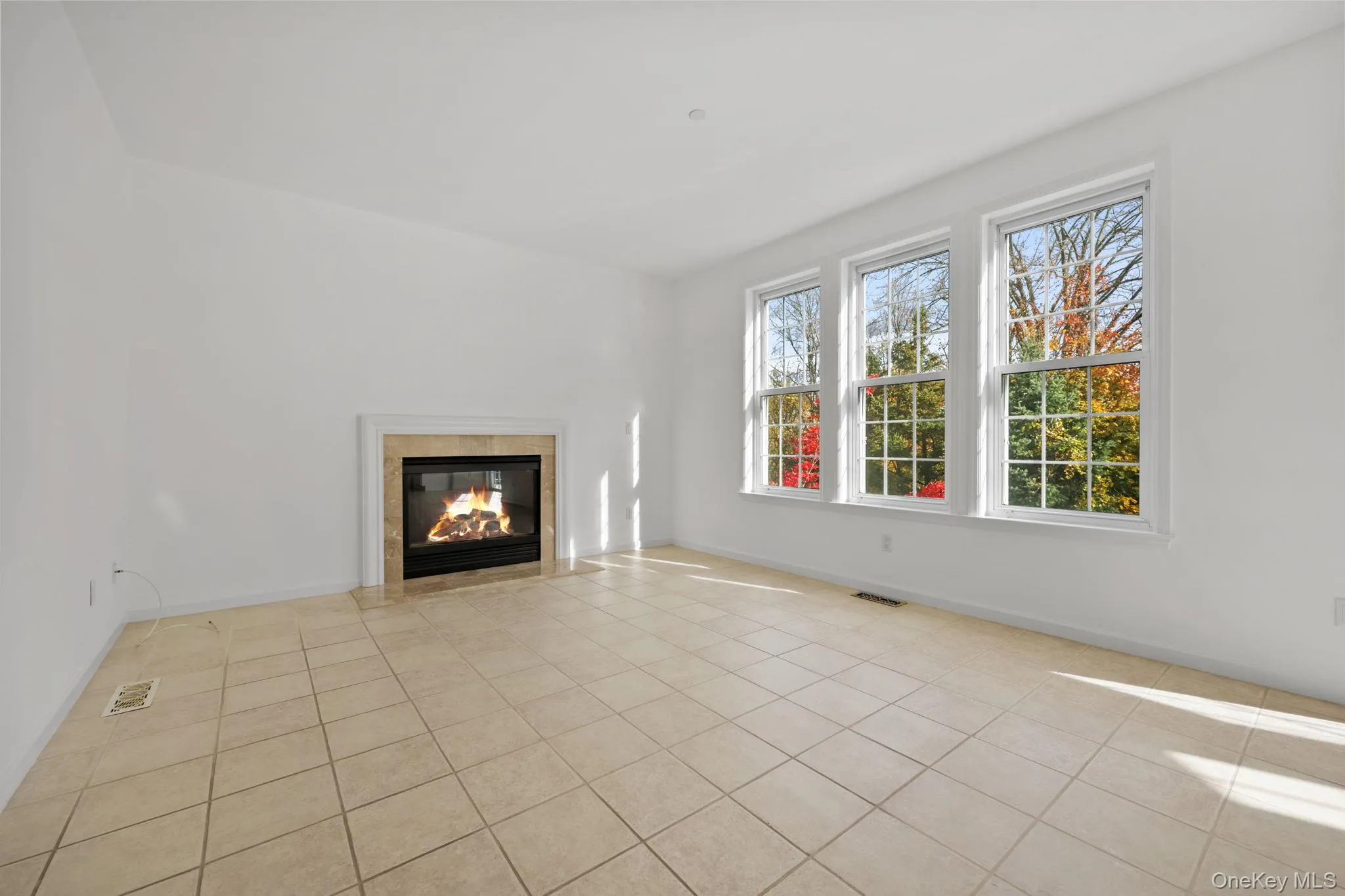 Unfurnished living room with light tile patterned floors and a premium fireplace Unfurnished living room with light tile patterned floors and a premium fireplace