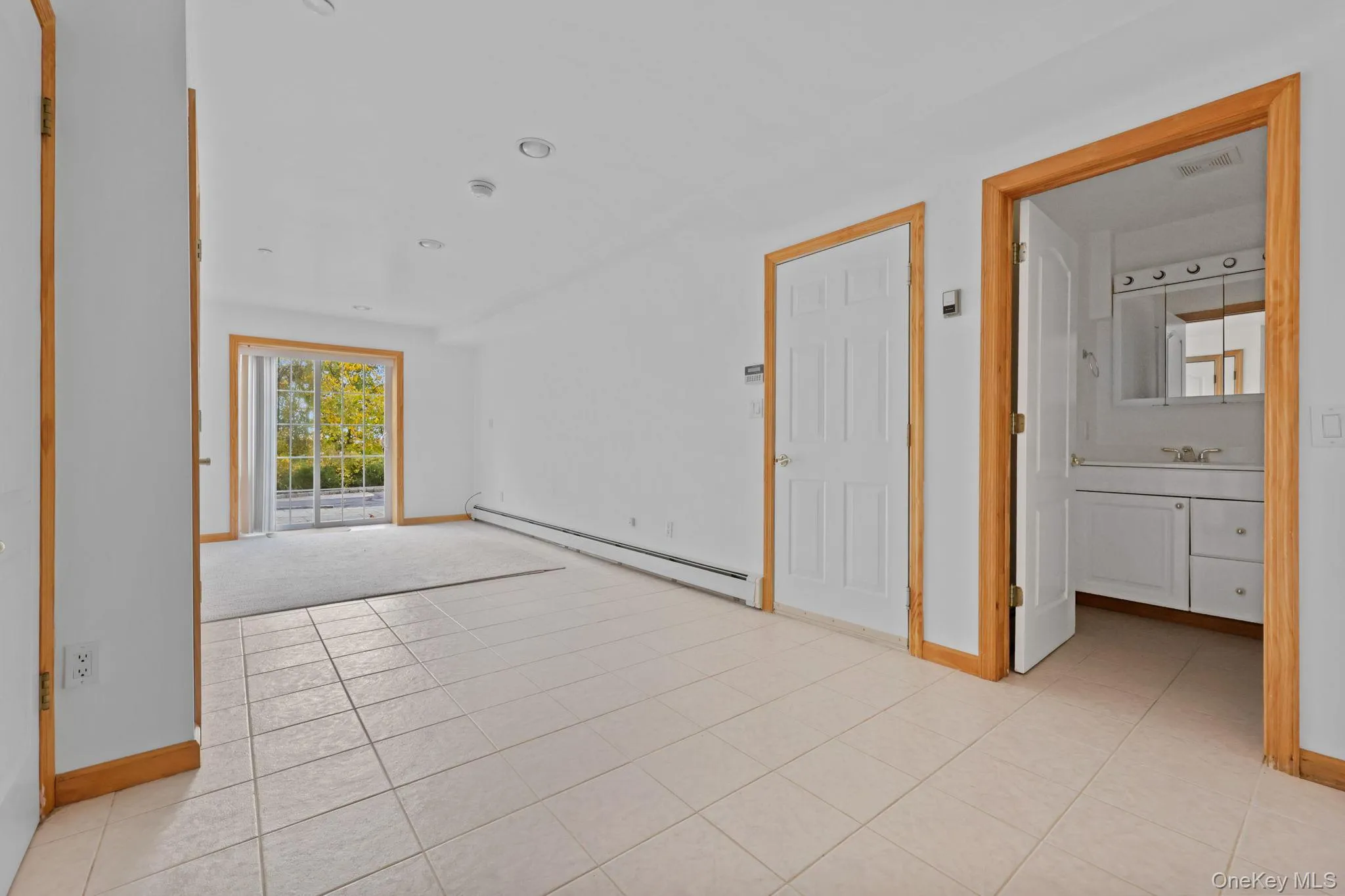 Unfurnished room with light tile patterned floors and baseboard heating Unfurnished room with light tile patterned floors and baseboard heating