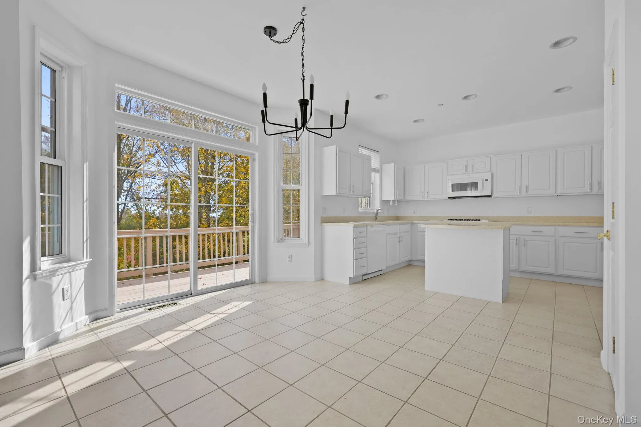 Kitchen featuring light countertops, white cabinetry, a chandelier, light tile patterned flooring, and decorative light fixtures Kitchen featuring light countertops, white cabinetry, a chandelier, light tile patterned flooring, and decorative light fixtures