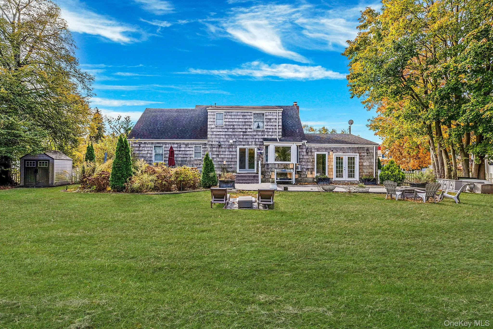 Rear view of house with a patio, a storage shed, a yard, roof with shingles, and a fire pit Rear view of house with a patio, a storage shed, a yard, roof with shingles, and a fire pit