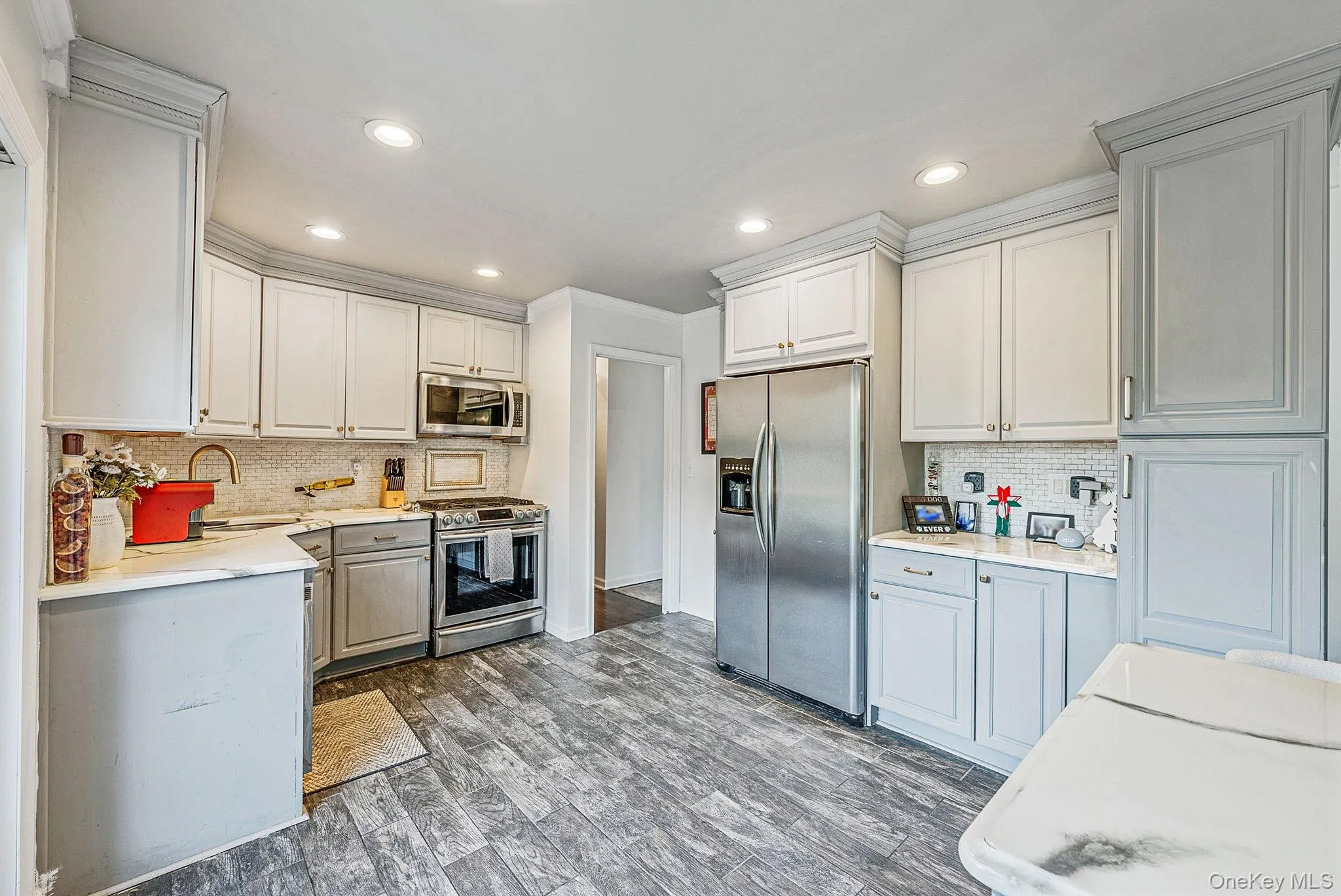 Kitchen with decorative backsplash, appliances with stainless steel finishes, dark wood-type flooring, recessed lighting, and light stone countertops Kitchen with decorative backsplash, appliances with stainless steel finishes, dark wood-type flooring, recessed lighting, and light stone countertops