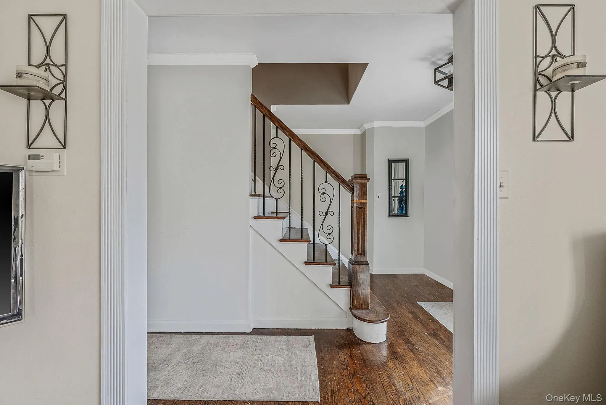 Foyer entrance featuring dark wood-style floors, crown molding, and stairway Foyer entrance featuring dark wood-style floors, crown molding, and stairway