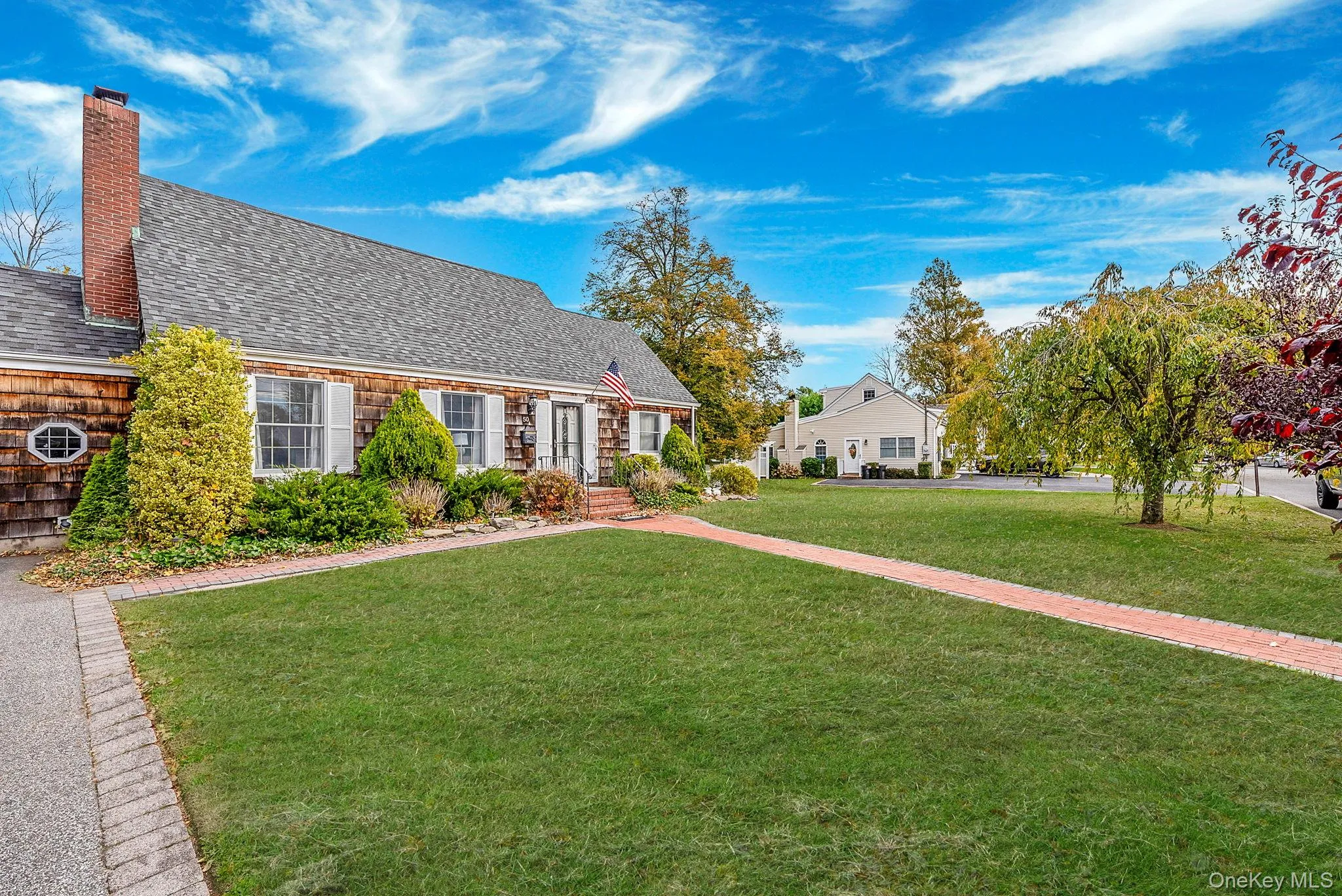 View of front facade featuring a front yard, roof with shingles, and a chimney View of front facade featuring a front yard, roof with shingles, and a chimney