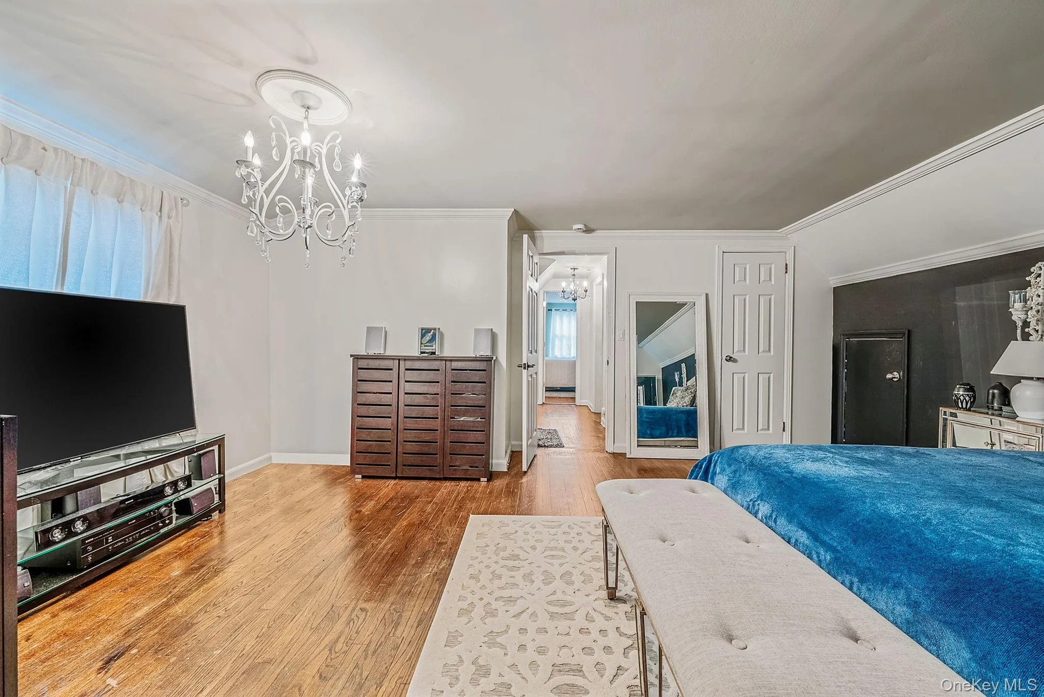 Bedroom featuring crown molding, a chandelier, and wood finished floors Bedroom featuring crown molding, a chandelier, and wood finished floors
