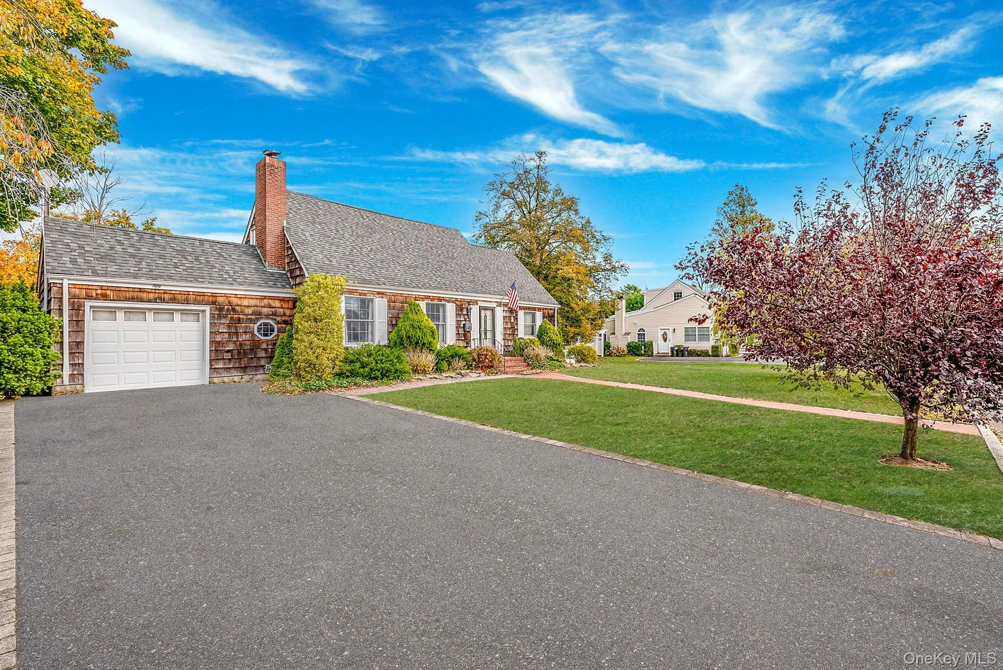 View of front facade with a front lawn, a garage, a shingled roof, a chimney, and driveway View of front facade with a front lawn, a garage, a shingled roof, a chimney, and driveway