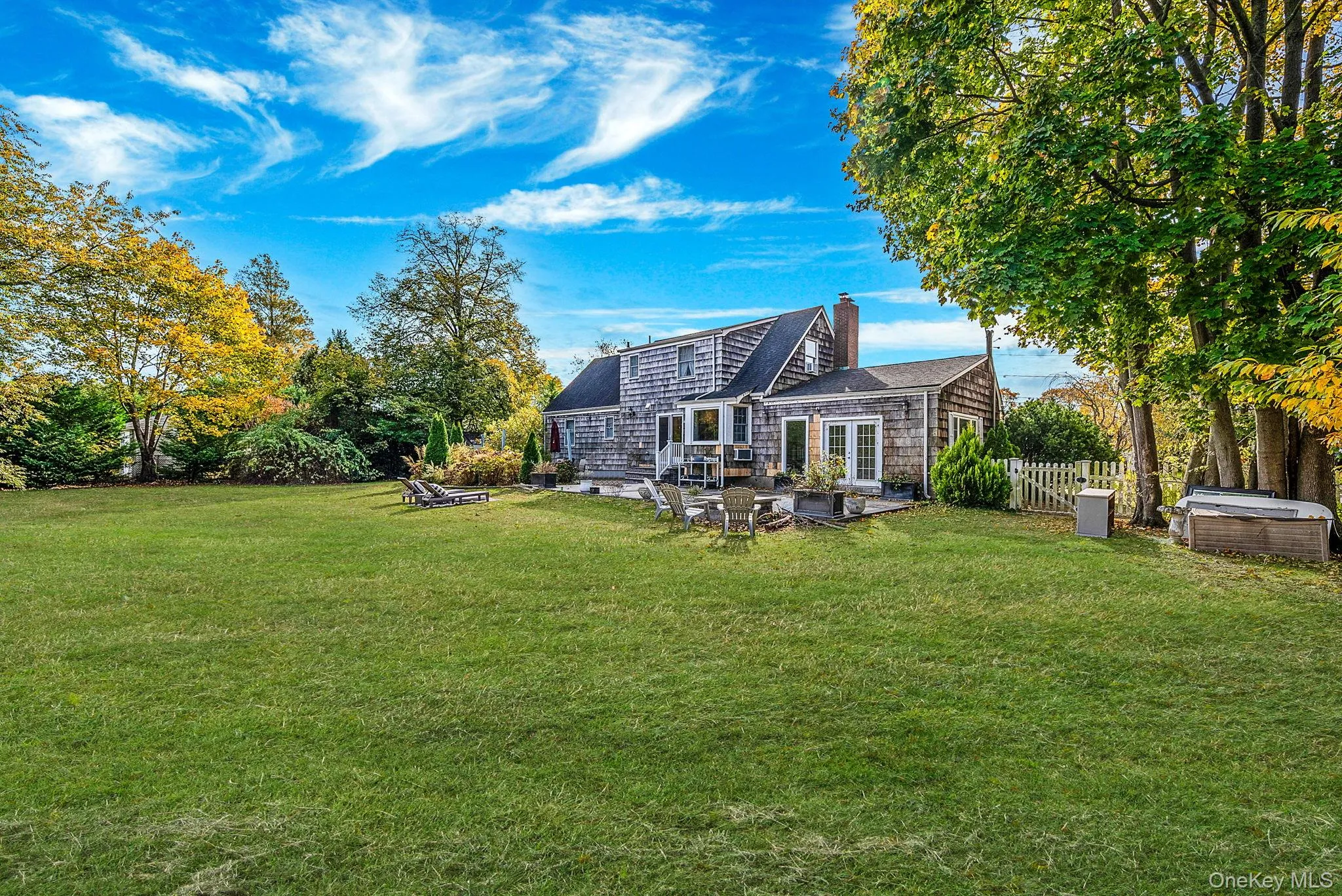 Rear view of house with a chimney, a patio, and a shingled roof Rear view of house with a chimney, a patio, and a shingled roof