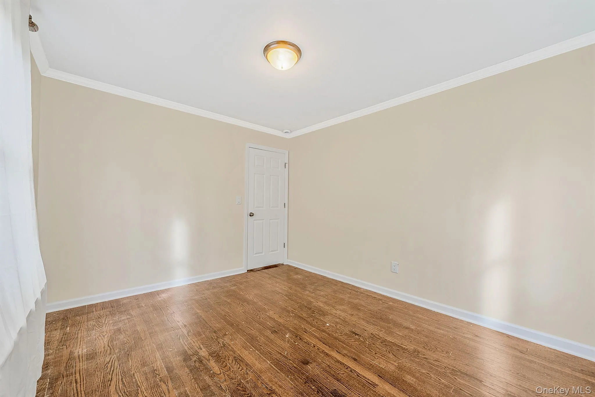Empty room featuring ornamental molding and wood finished floors Empty room featuring ornamental molding and wood finished floors