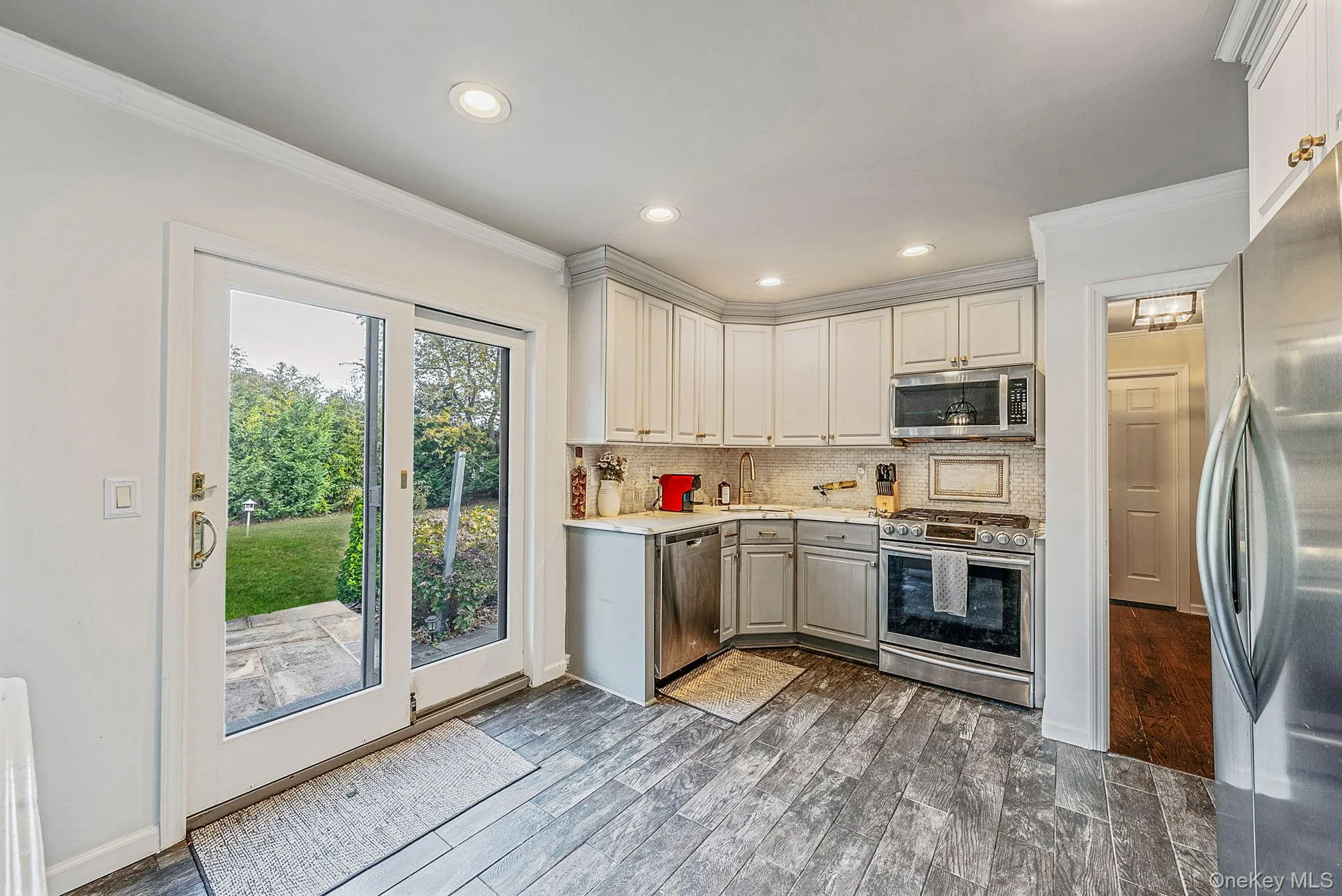 Kitchen with crown molding, stainless steel appliances, backsplash, dark wood-style flooring, and recessed lighting Kitchen with crown molding, stainless steel appliances, backsplash, dark wood-style flooring, and recessed lighting