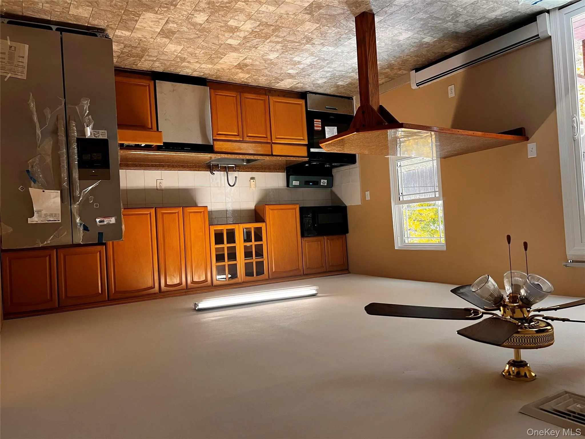 Kitchen featuring fridge, baseboard heating, range, backsplash, and glass insert cabinets Kitchen featuring fridge, baseboard heating, range, backsplash, and glass insert cabinets