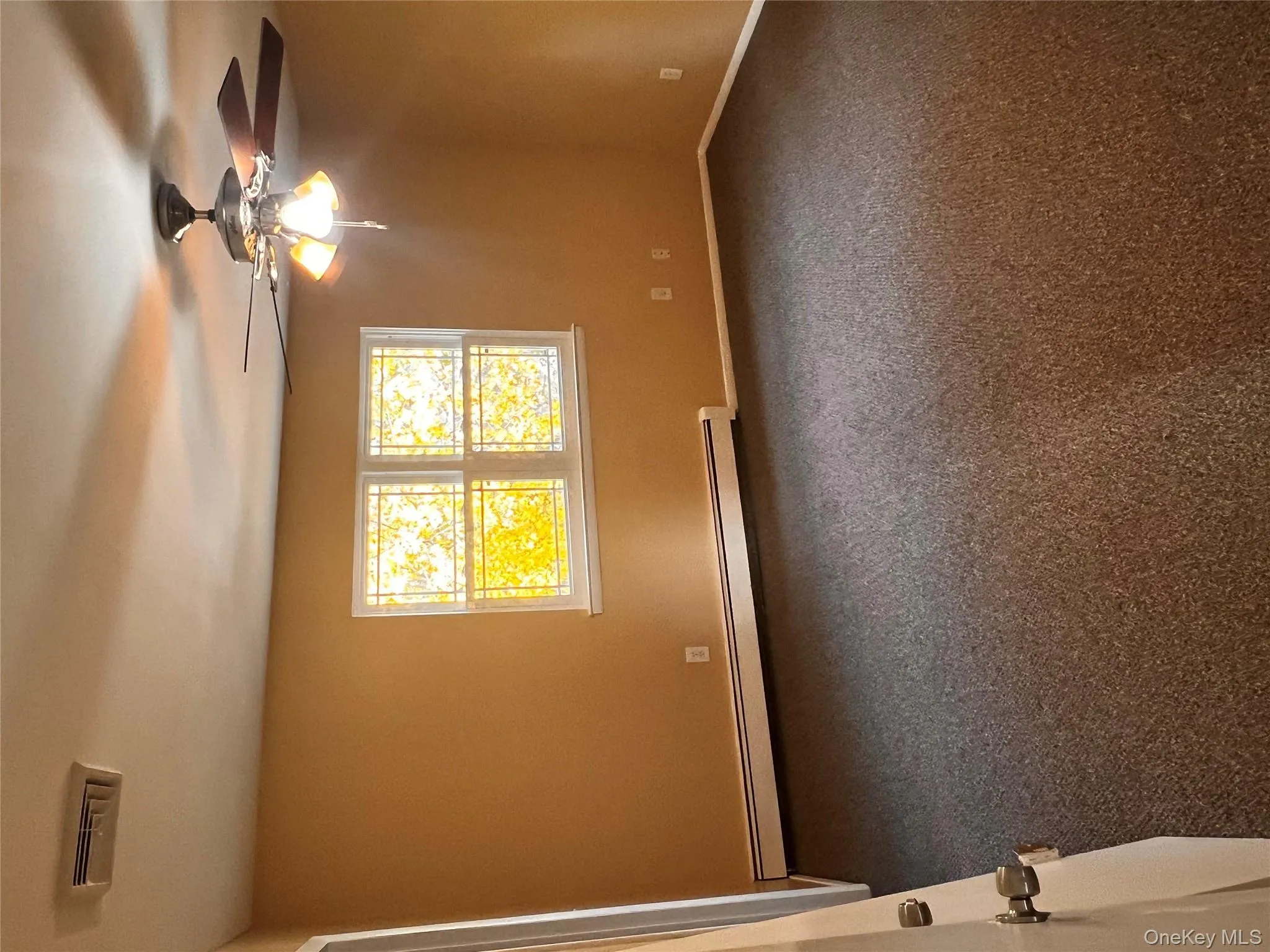 Unfurnished room with dark colored carpet, baseboard heating, and a ceiling fan Unfurnished room with dark colored carpet, baseboard heating, and a ceiling fan