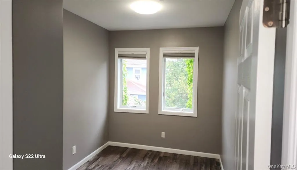 Unfurnished room featuring dark wood-type flooring and baseboards Unfurnished room featuring dark wood-type flooring and baseboards