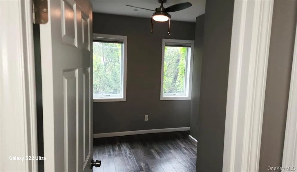 Empty room featuring dark wood-style floors and a ceiling fan Empty room featuring dark wood-style floors and a ceiling fan