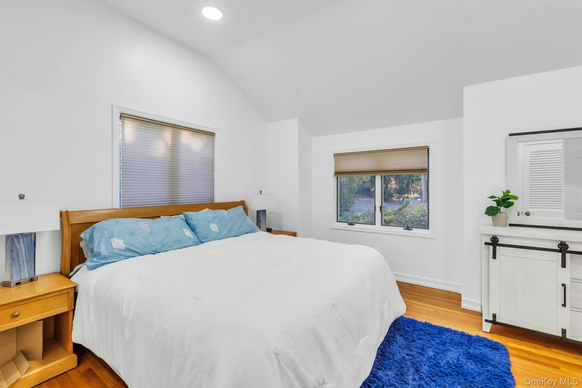 Bedroom with light wood-style floors, vaulted ceiling, and recessed lighting Bedroom with light wood-style floors, vaulted ceiling, and recessed lighting