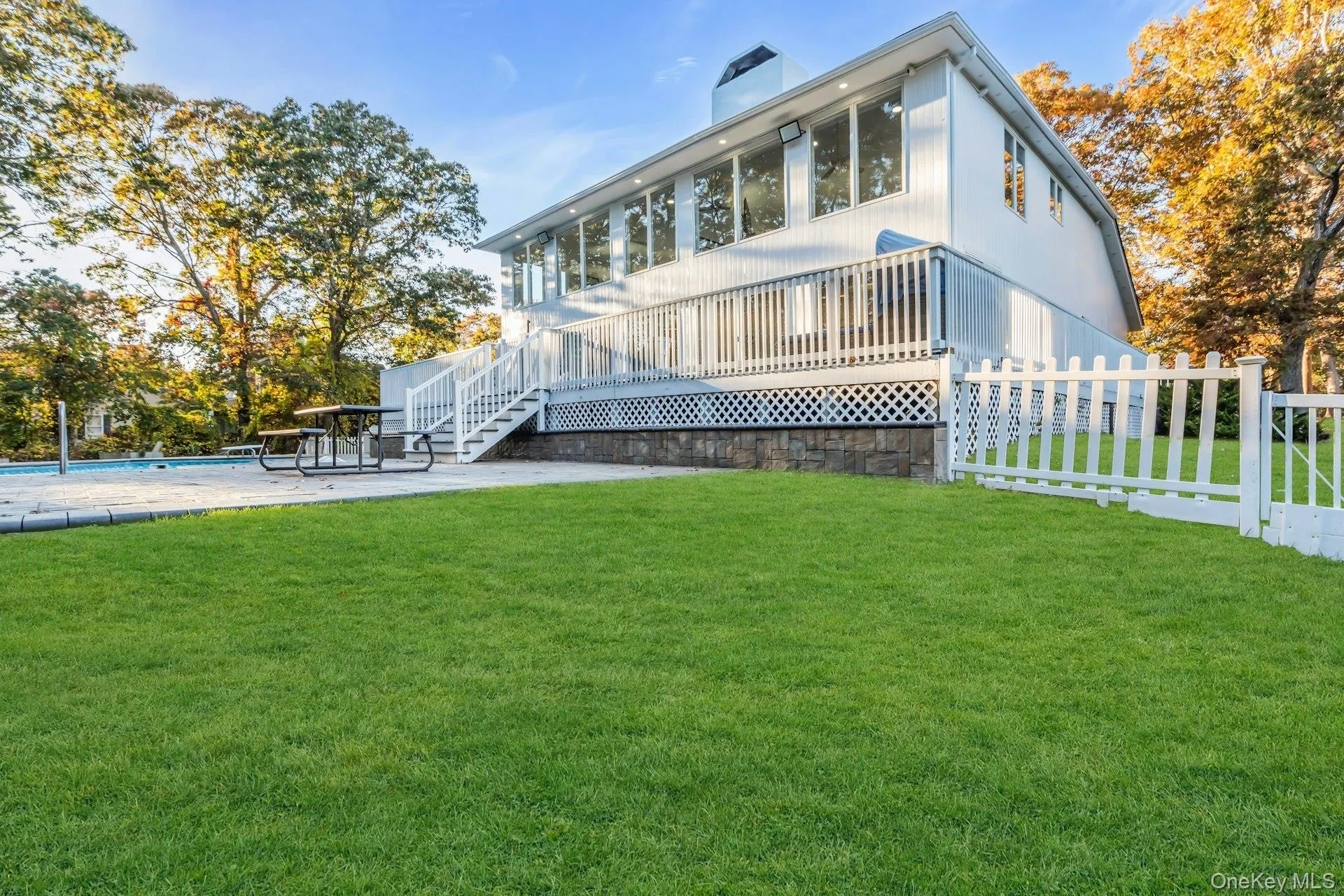 Rear view of house with an outdoor pool, a chimney, a deck, stairs, and a patio Rear view of house with an outdoor pool, a chimney, a deck, stairs, and a patio