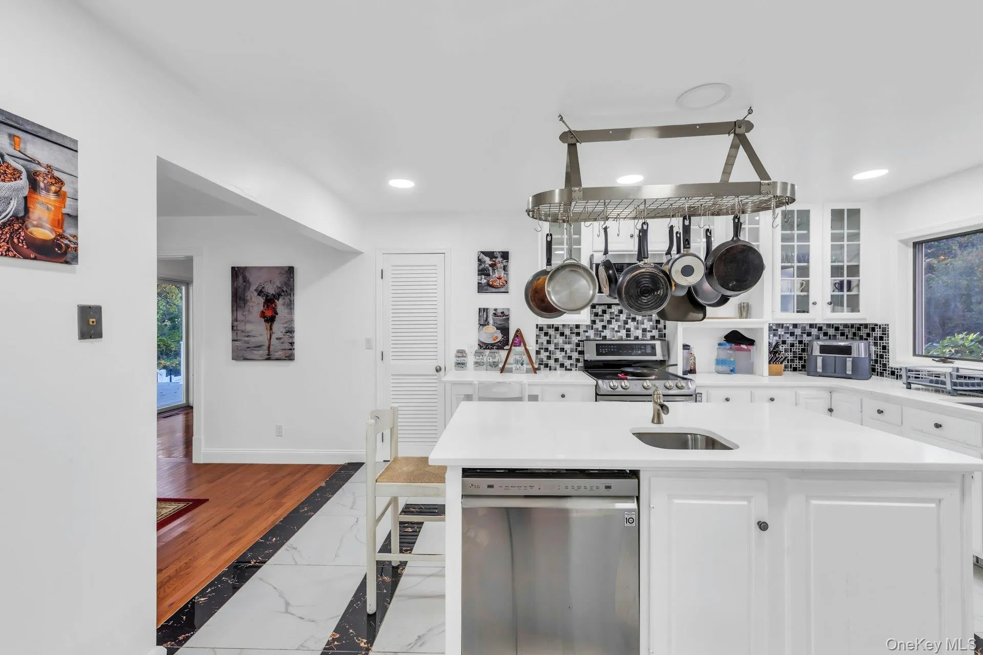 Kitchen with white cabinetry, glass insert cabinets, stainless steel appliances, tasteful backsplash, and recessed lighting Kitchen with white cabinetry, glass insert cabinets, stainless steel appliances, tasteful backsplash, and recessed lighting