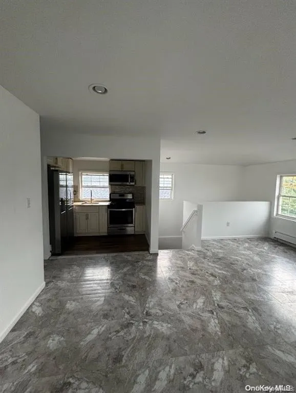 Unfurnished living room featuring baseboards and baseboard heating Unfurnished living room featuring baseboards and baseboard heating